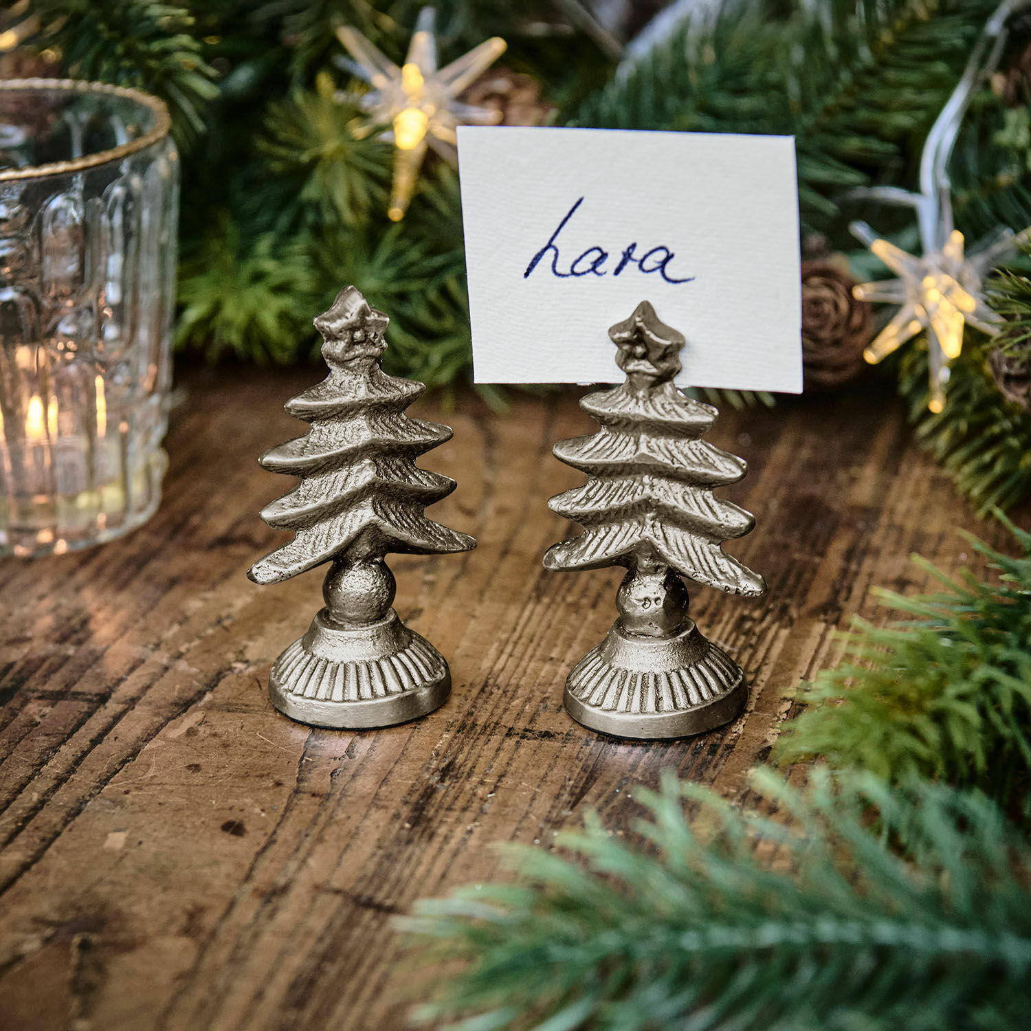 Kaarthouder set van 2 Leovian Zilverkleurige metalen kaartjeshouders in kerstboomvorm op houten tafel met kerstdecoratie