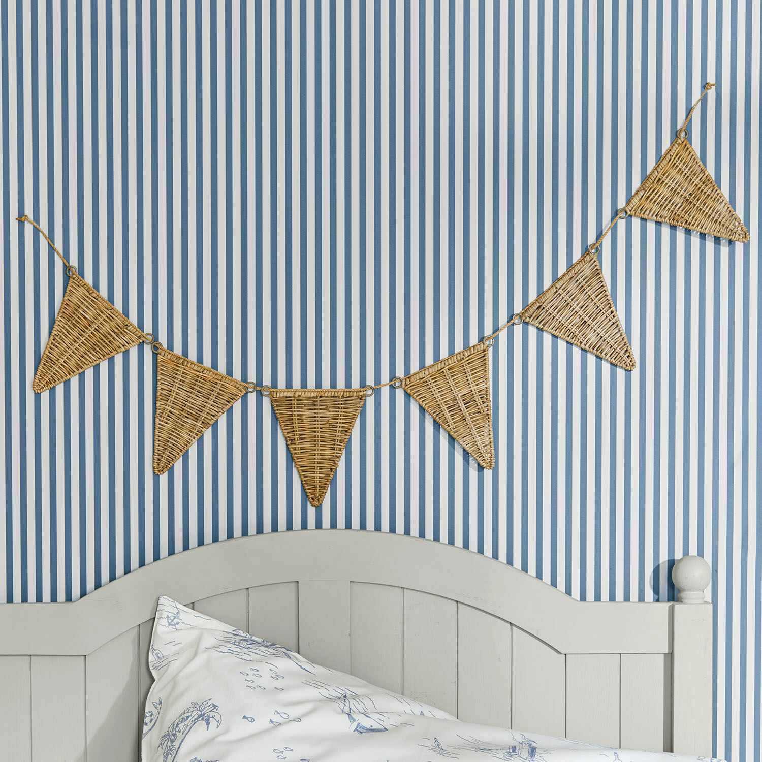 Vlaggenlijn Anglemont Decoratieve slinger van gevlochten riet in driehoekige vorm aan blauw-wit gestreepte muur in slaapkamer
