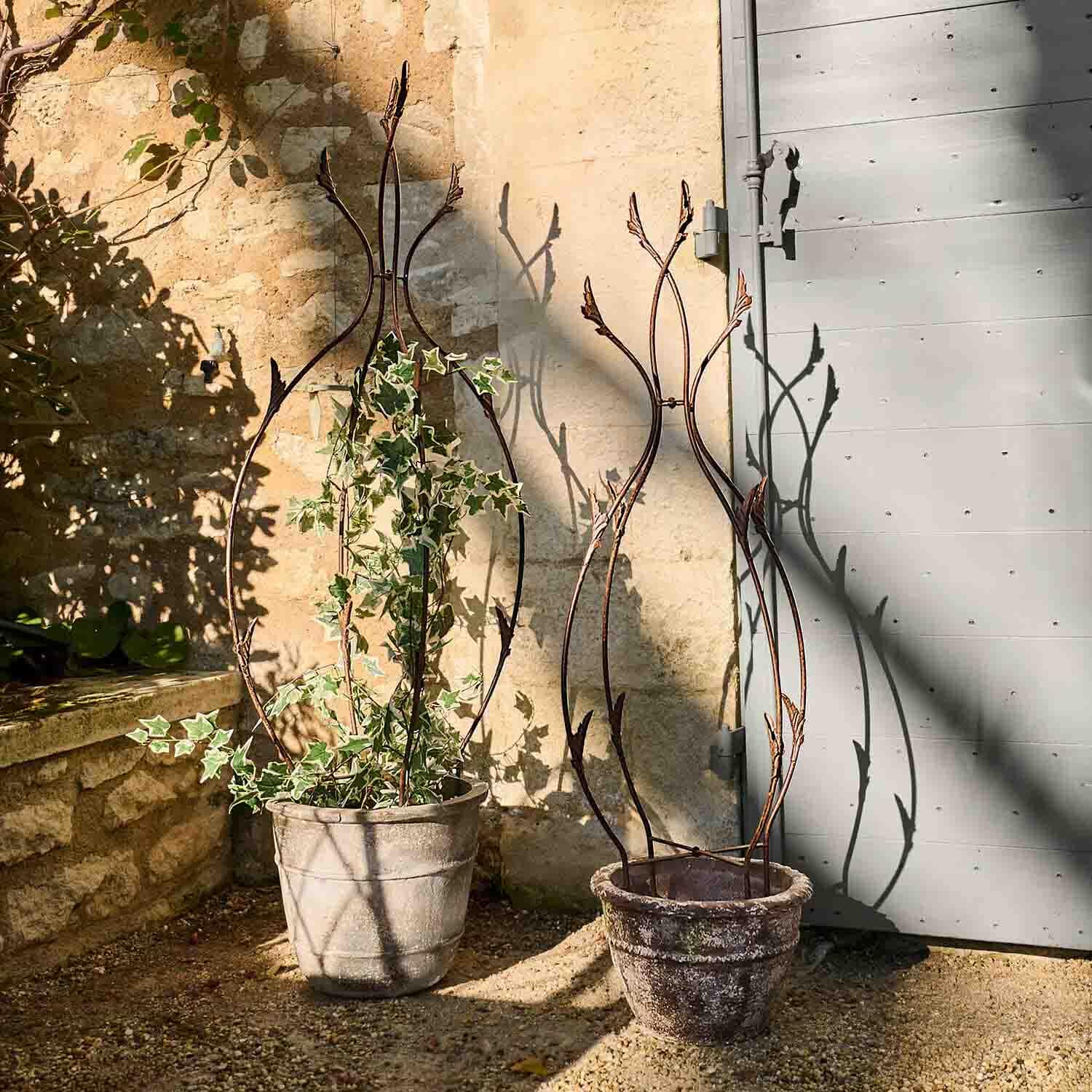 Decoratieve metalen plantensteun met bladmotief in roestkleur, geschikt voor potplanten buiten