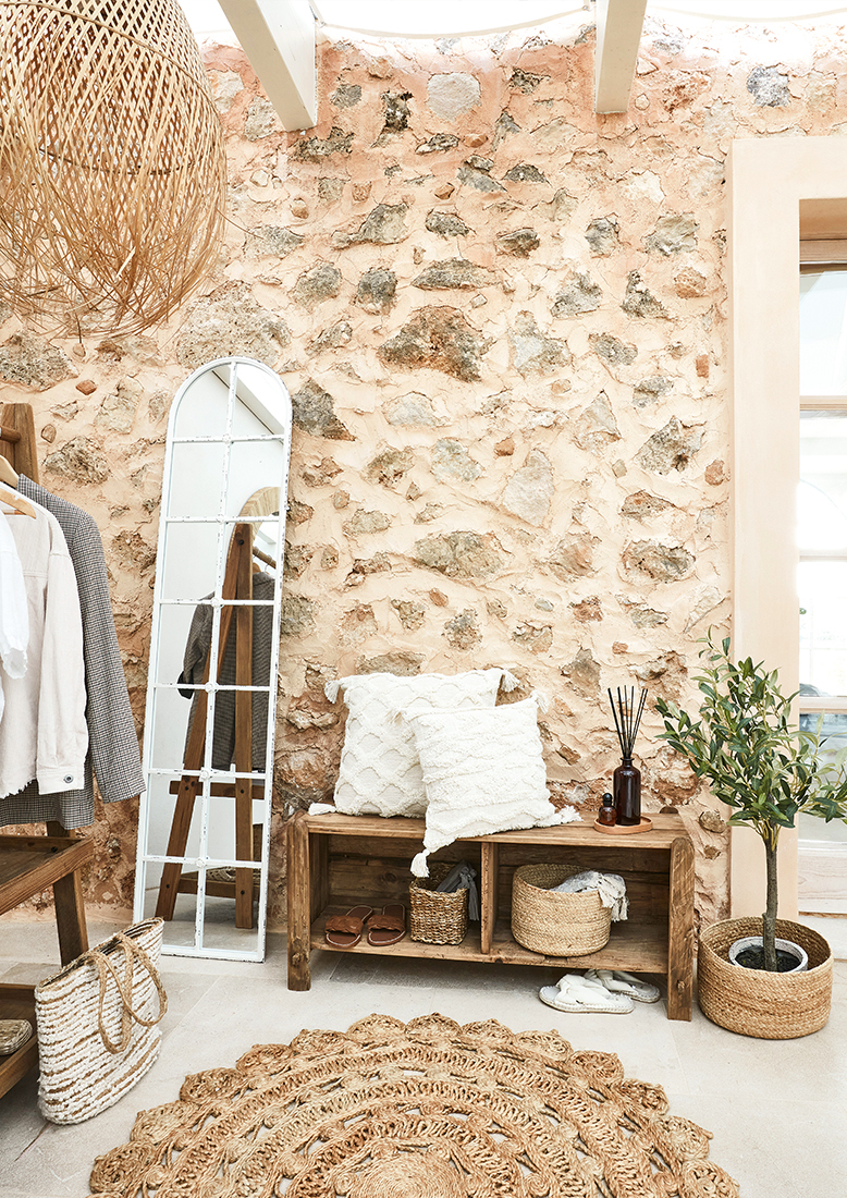 Gezellige hoek met houten bank, witte kussens en natuurlijke jute vloerkleed in boho stijl