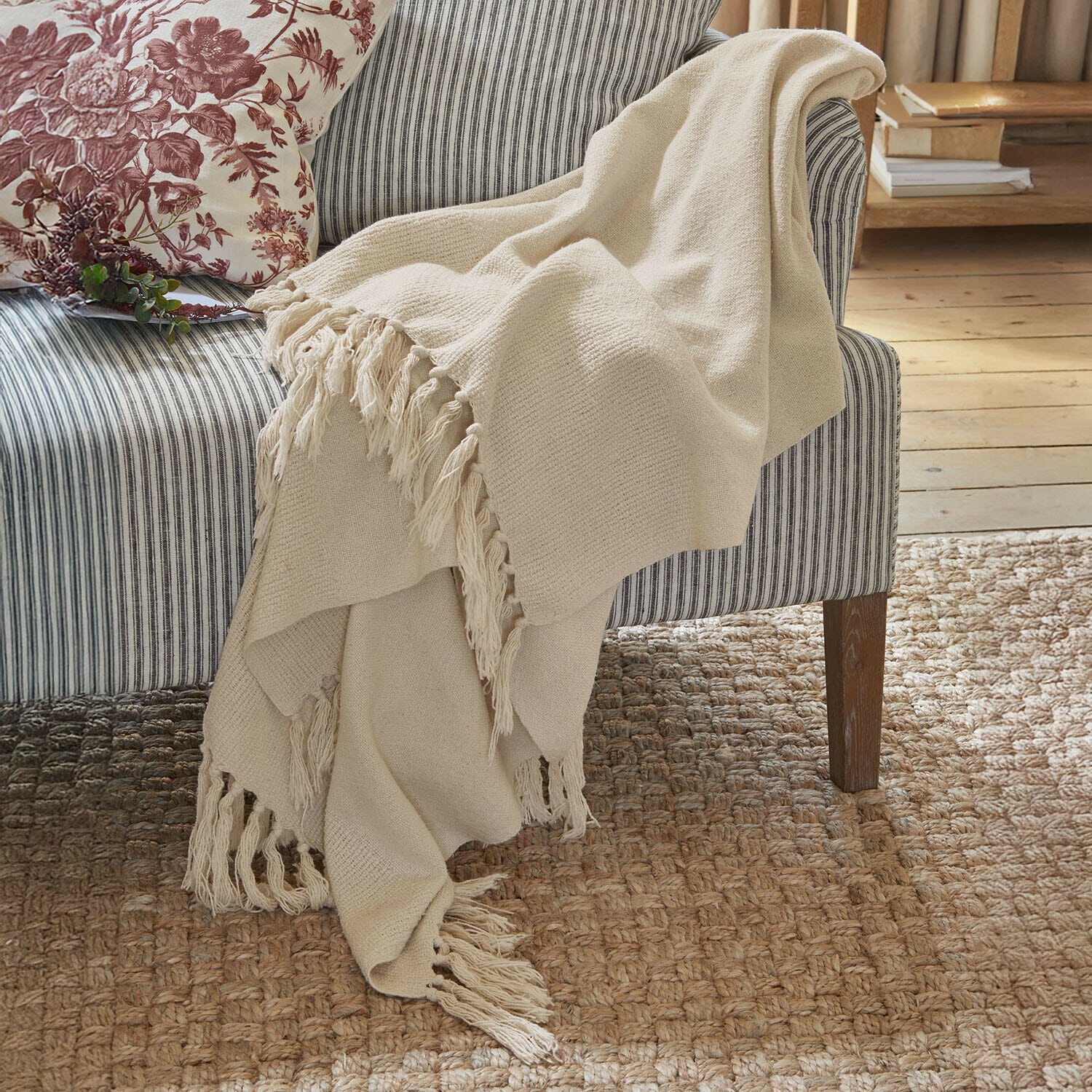 Plaid Skandira Beige zachte deken met franjes op een grijze gestreepte bank in een gezellige kamer
