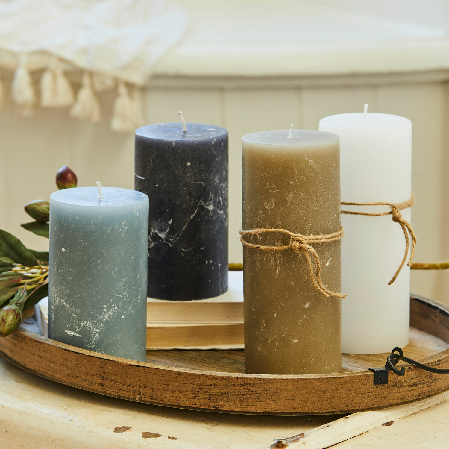 Set van vier kaarsen in blauw, zwart, bruin en wit op een decoratief houten dienblad