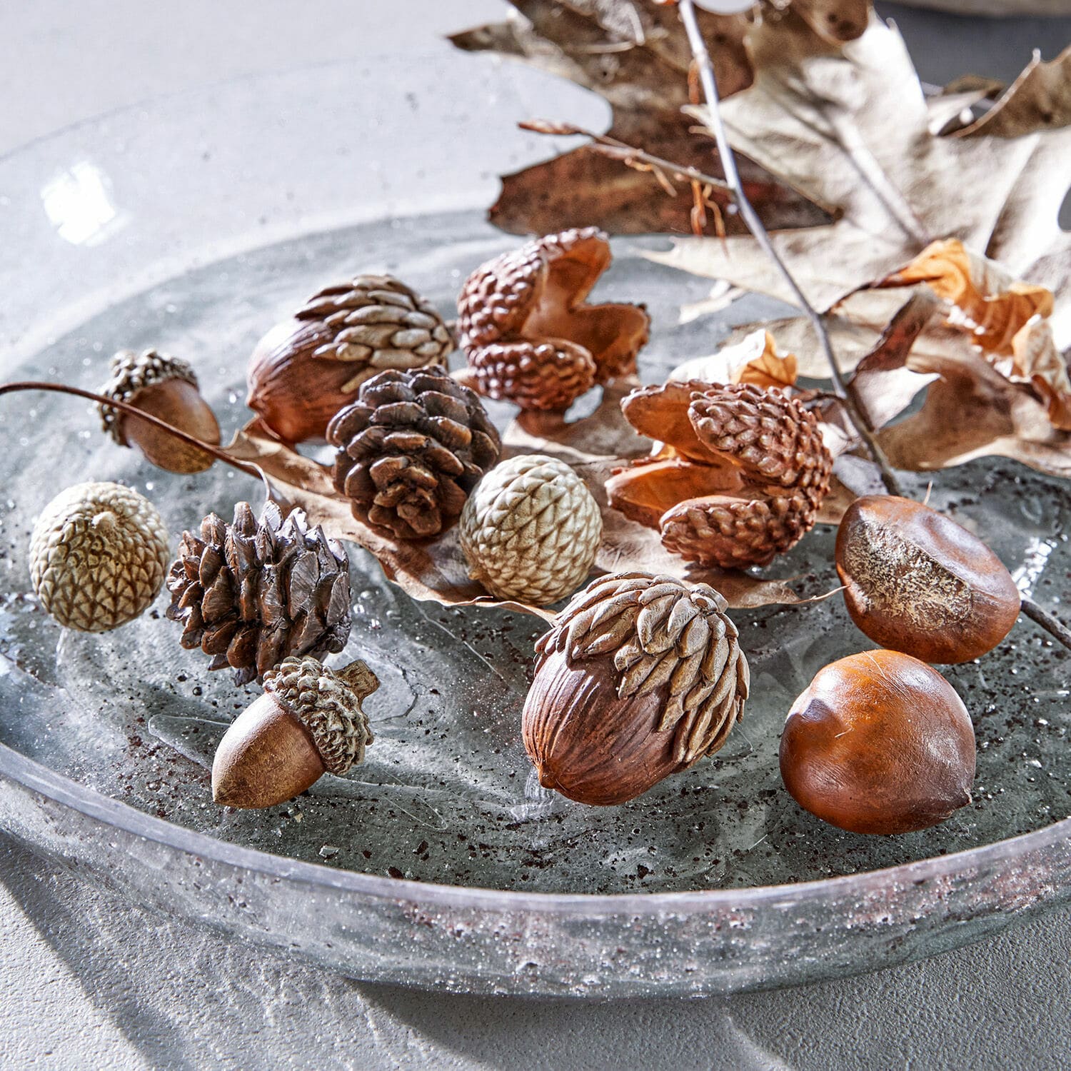 Herfstdecoratie set van 12 Vibius Decoratieve noten en dennenappels in natuurlijke bruine tinten op glazen bord voor herfstdecoratie