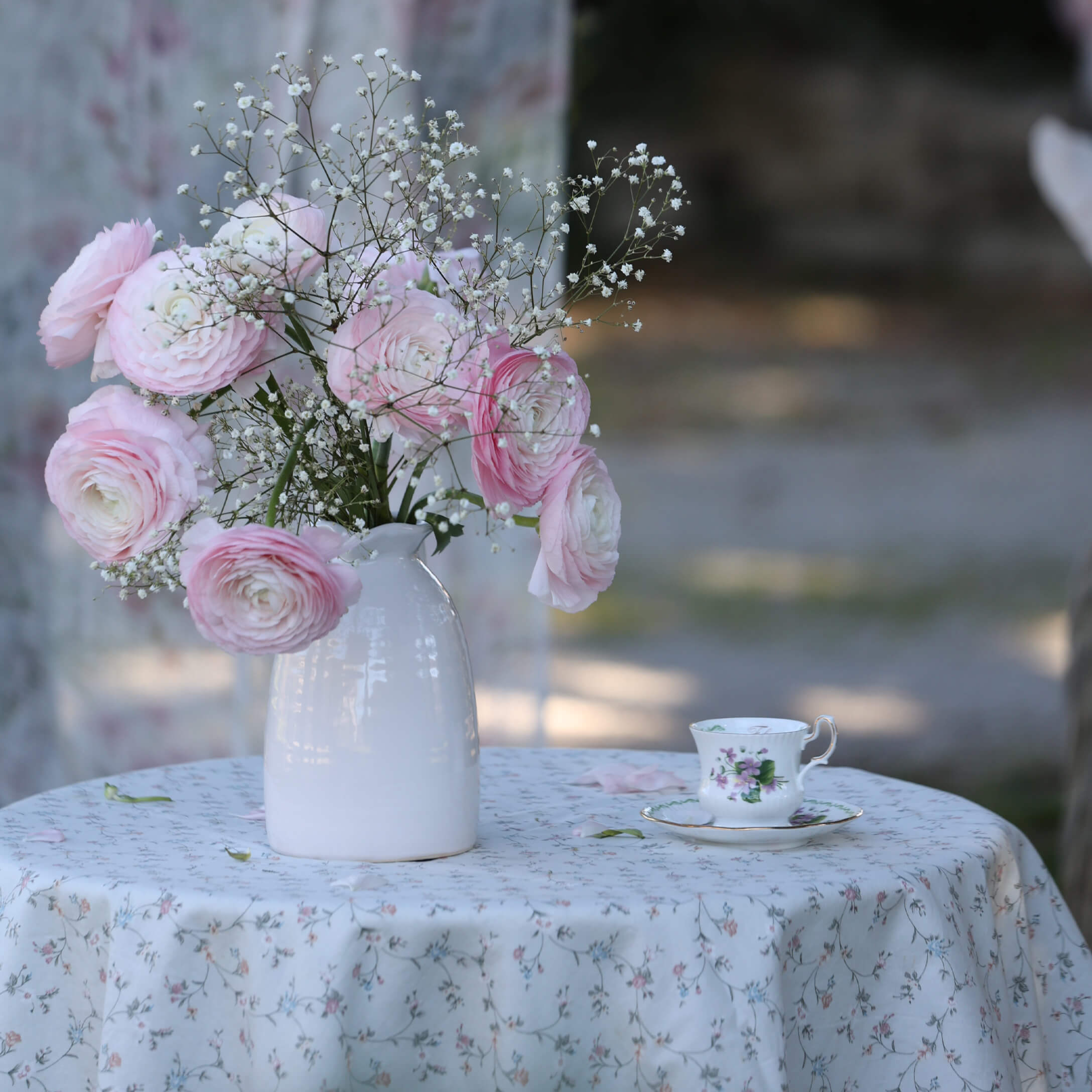 Boeket van roze en witte bloemen in witte keramische vaas op tafel met bloemen tafelkleed