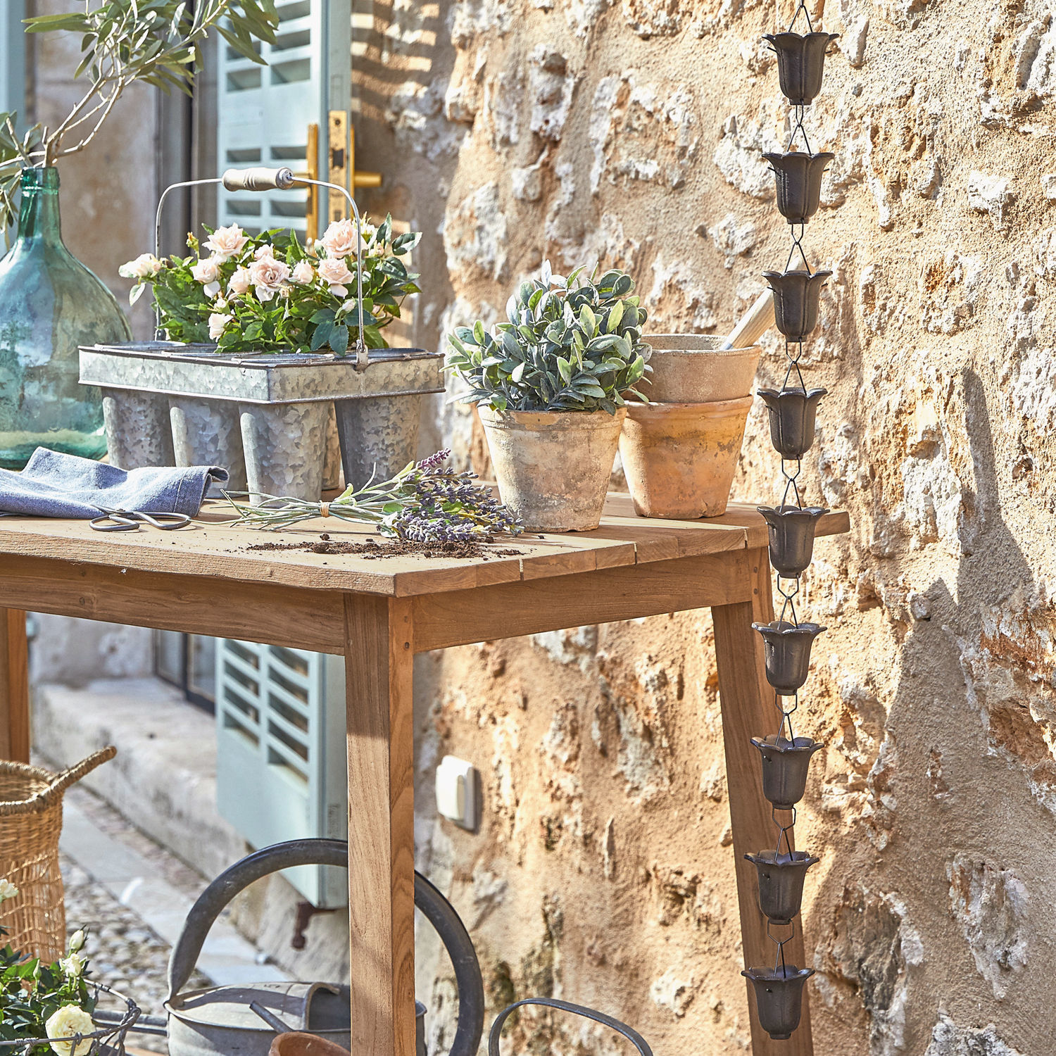 Regenafvoerketting Shimon Houten tuintafel met terracotta potten en metalen plantenbak in rustieke setting