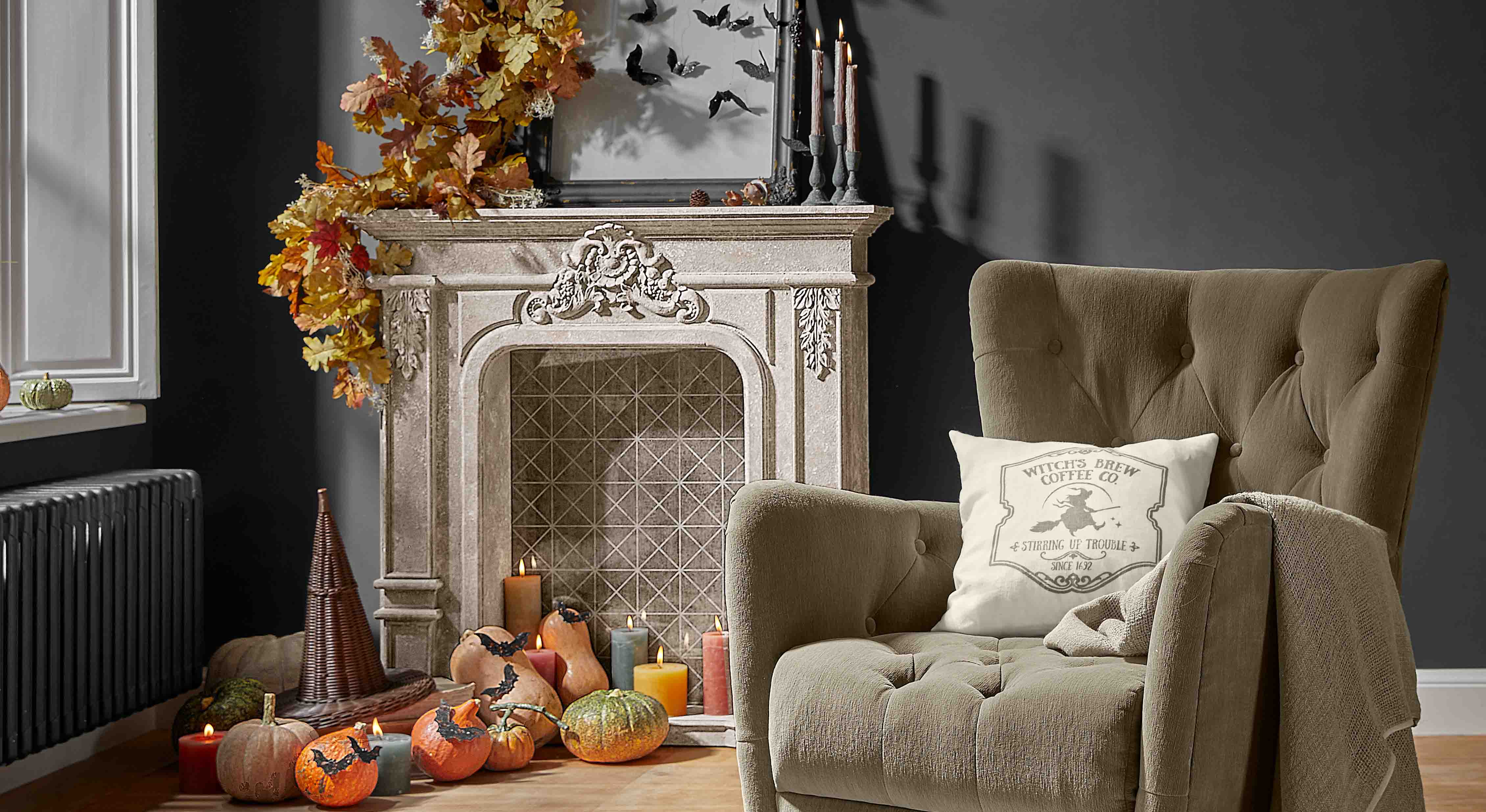 Decoratieve open haard met herfstbladeren, pompoenen en kaarsen in een gezellige woonkamer met beige fauteuil