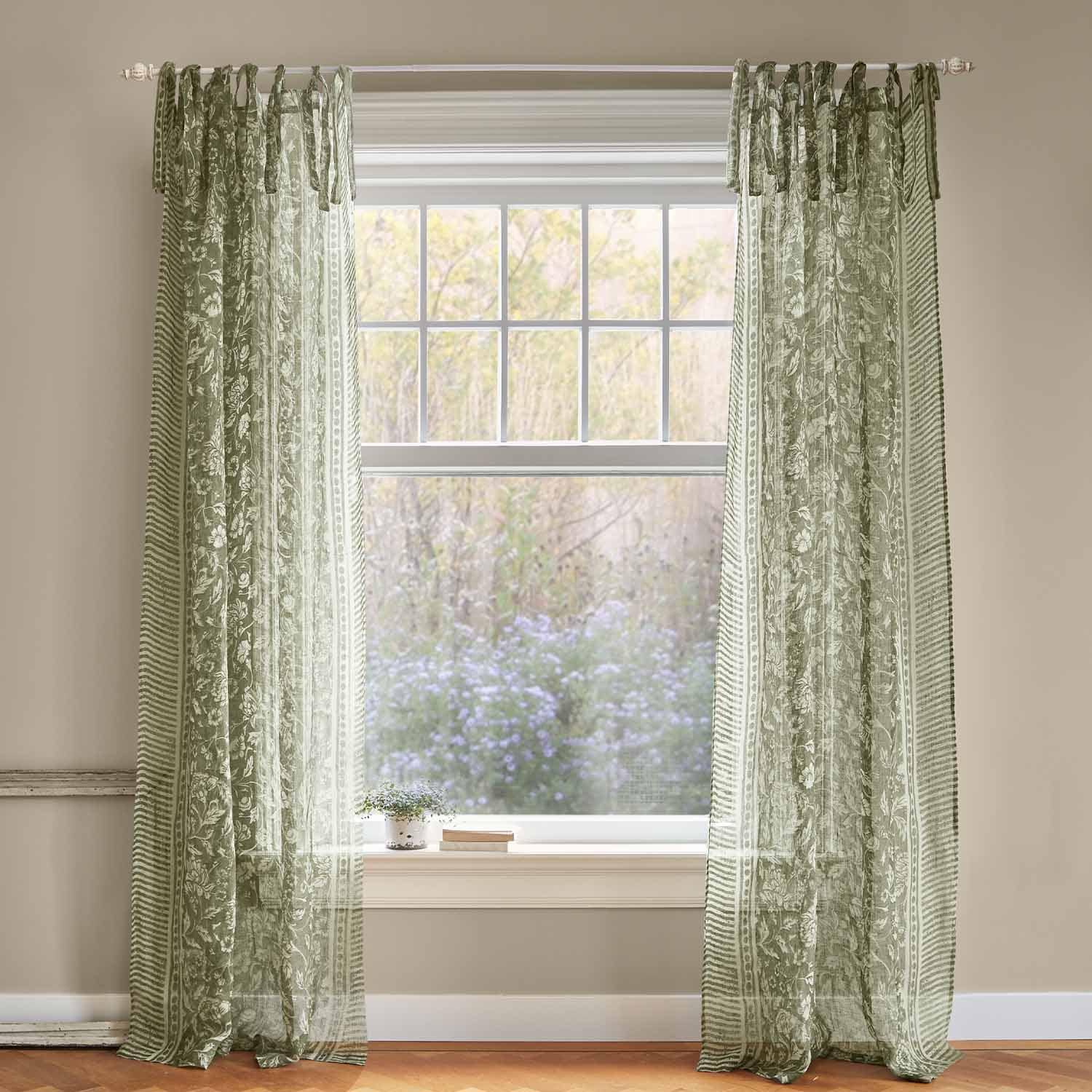Groene, transparante gordijnen met bloemenpatroon aan het raam, lichte interieurdecoratie van stof.