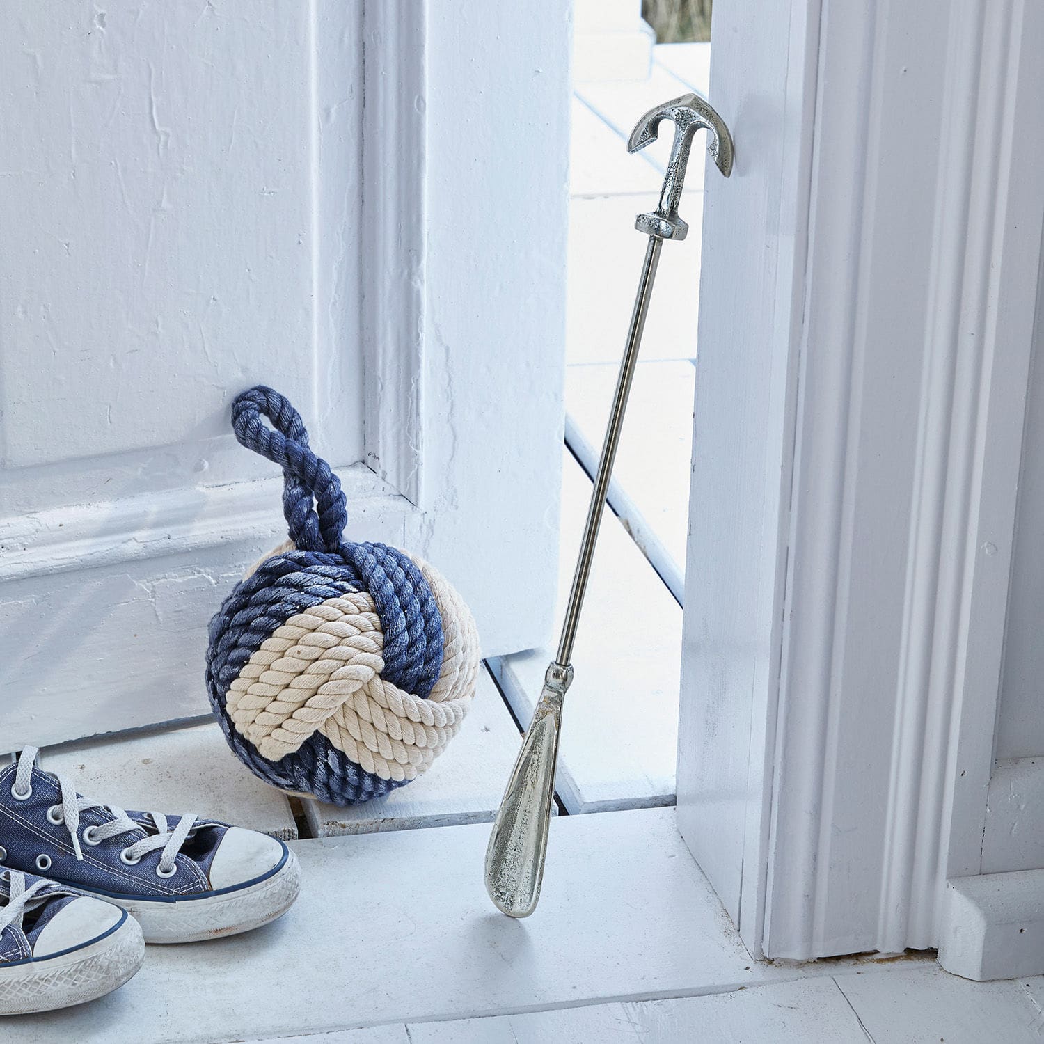 Schoenlepel Priam Metalen deurstop in anker vorm met blauw-beige touwgewicht op witte vloer