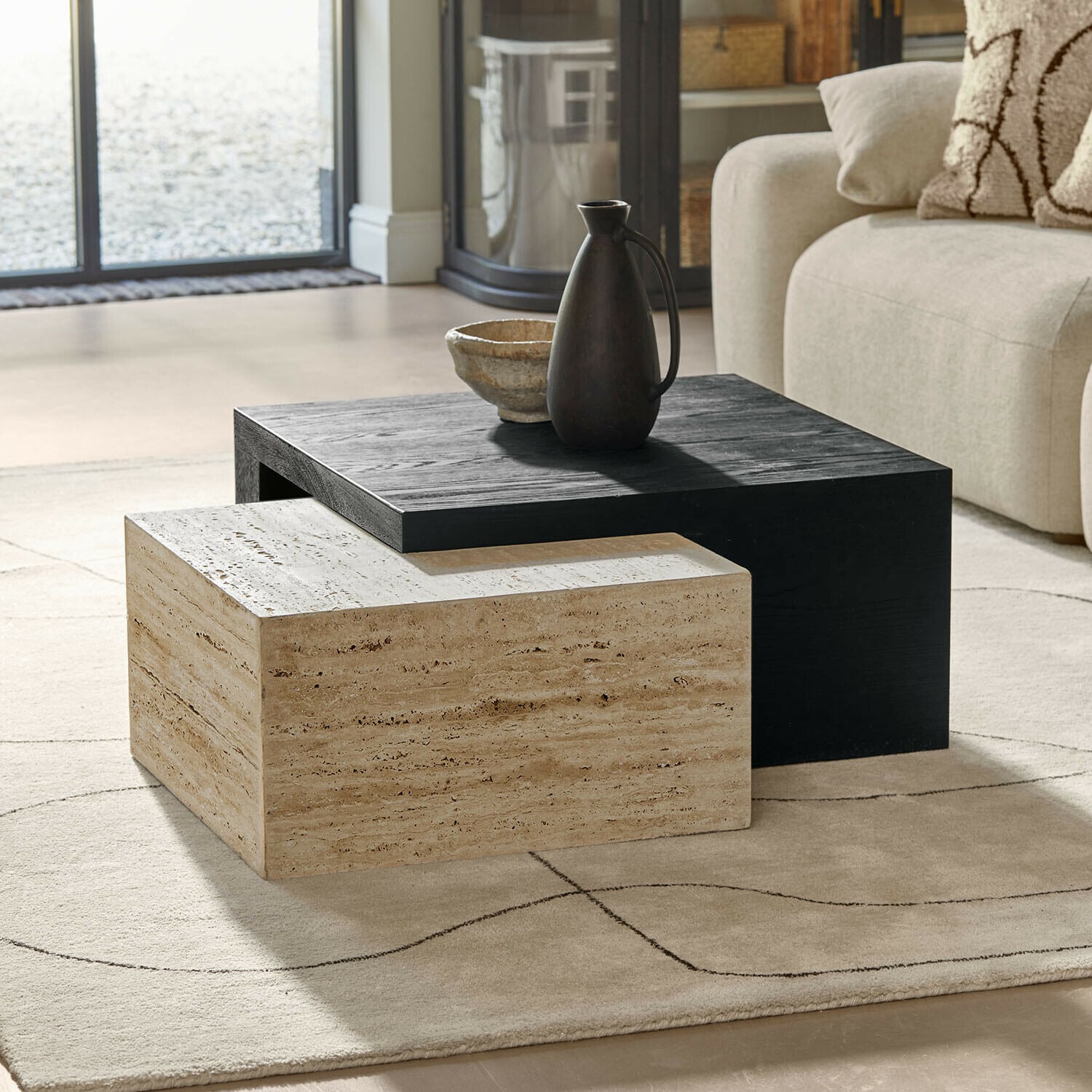 Moderne salontafels van zwart hout en beige steen op een lichte vloerkleed in woonkamer