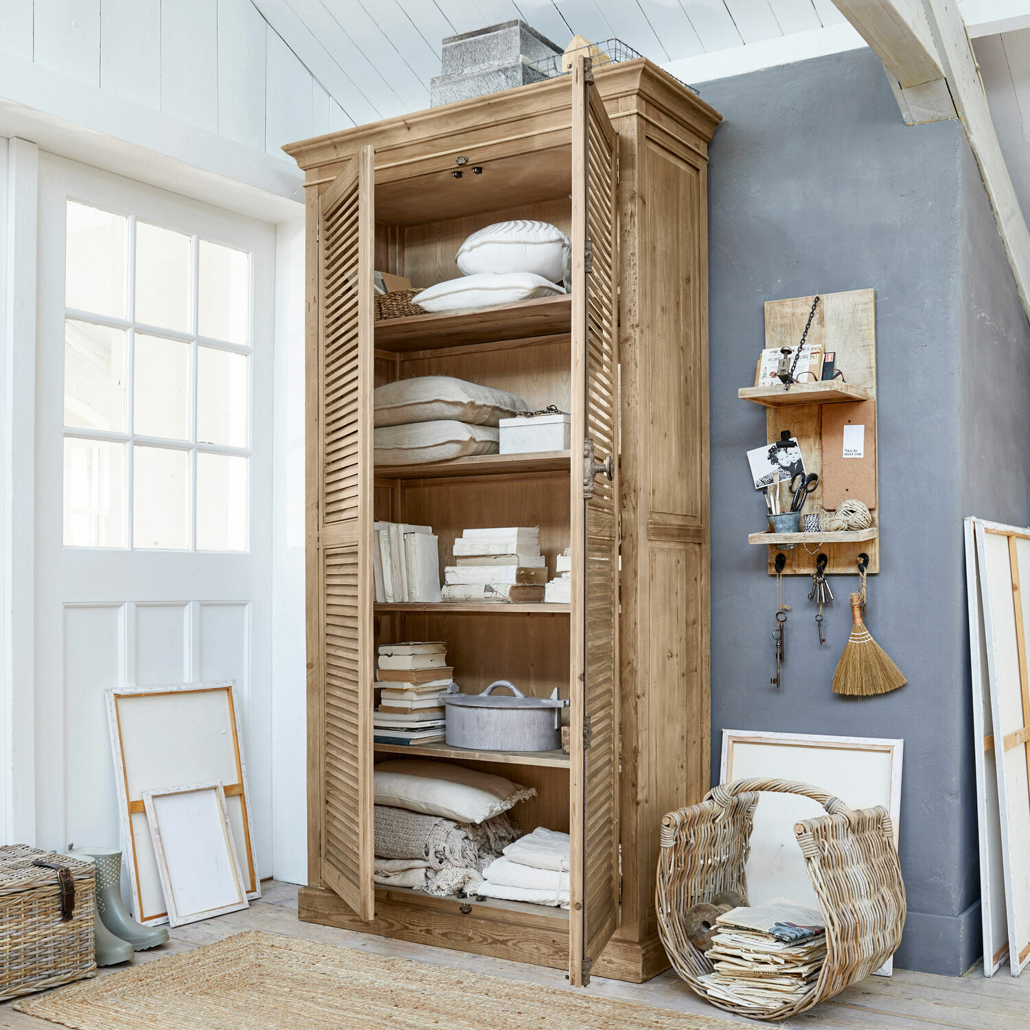 Kast Farnham Houten kast met luikdeuren in natuurlijke kleur, gevuld met kussens en boeken in lichte kamer