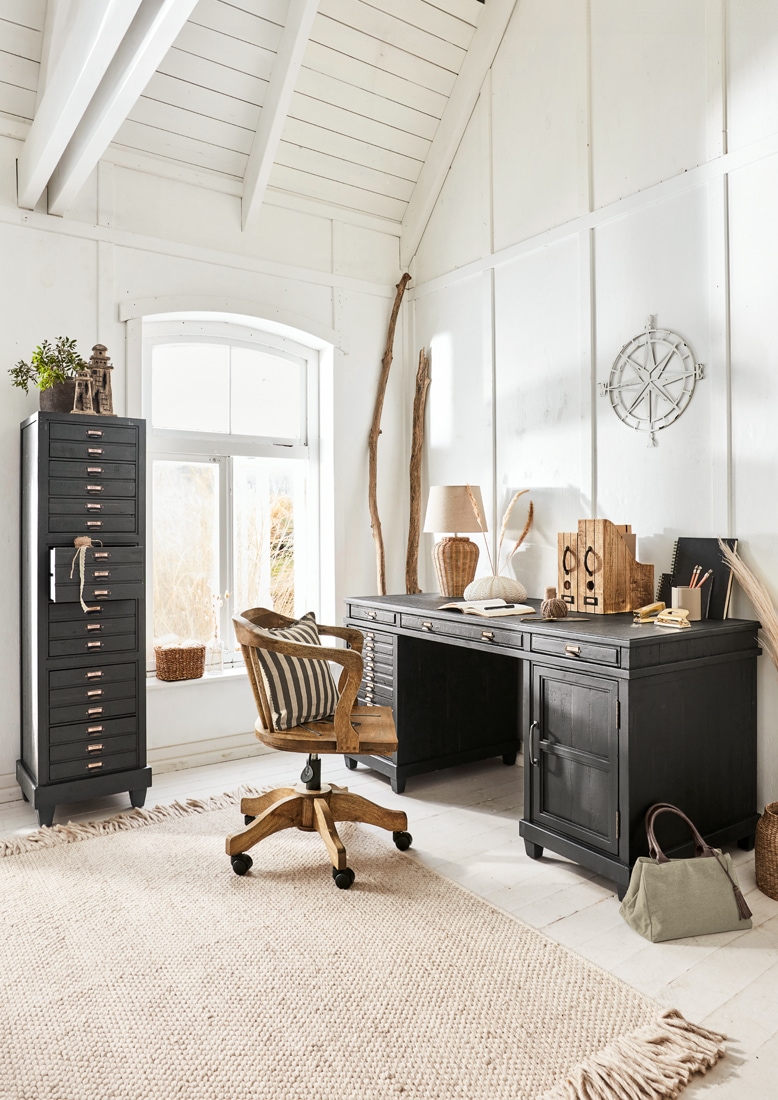 Zwart houten bureau en hoge ladekast in lichte, gezellige werkkamer