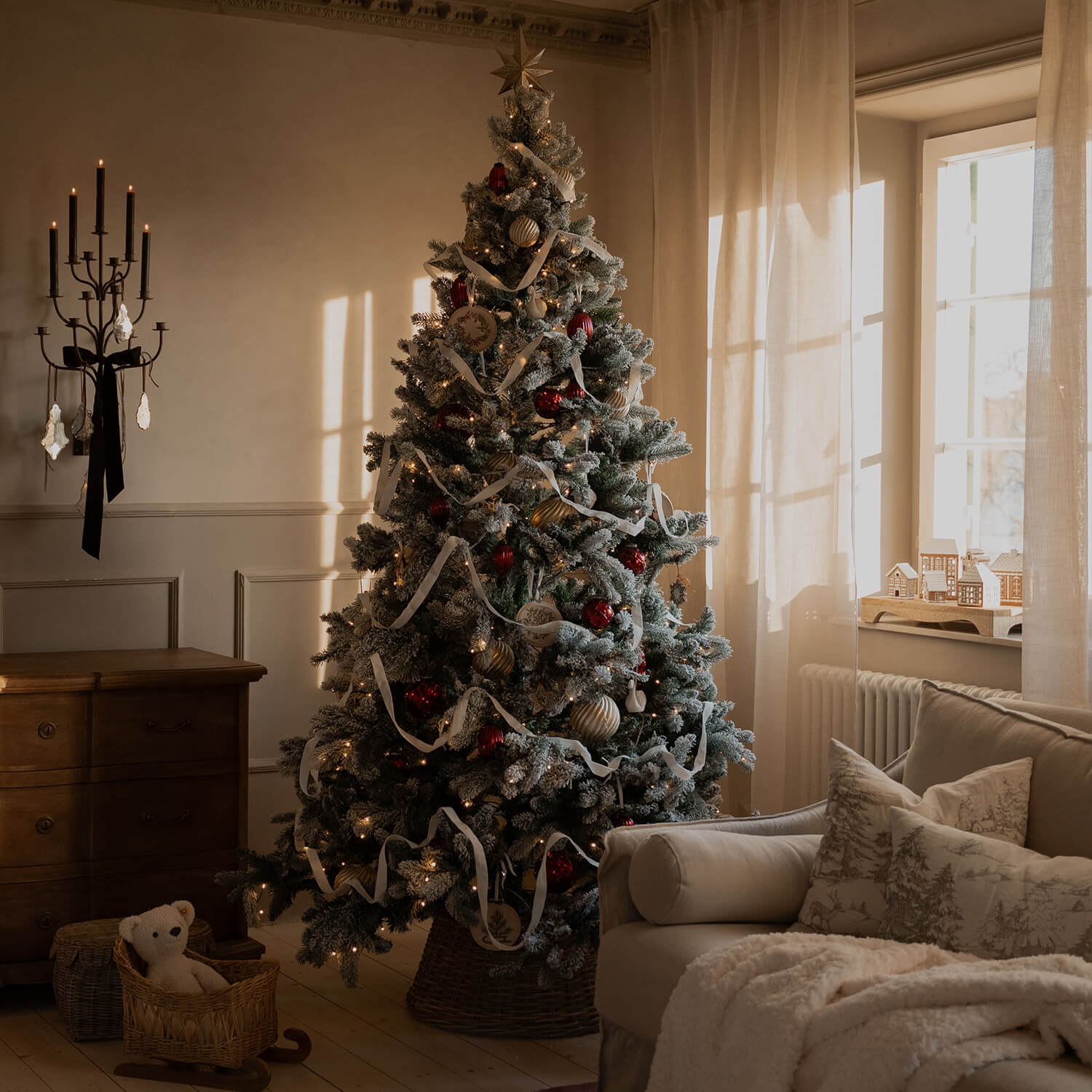 Gezellige woonkamer met besneeuwde kerstboom versierd met rode en gouden ballen en witte lint
