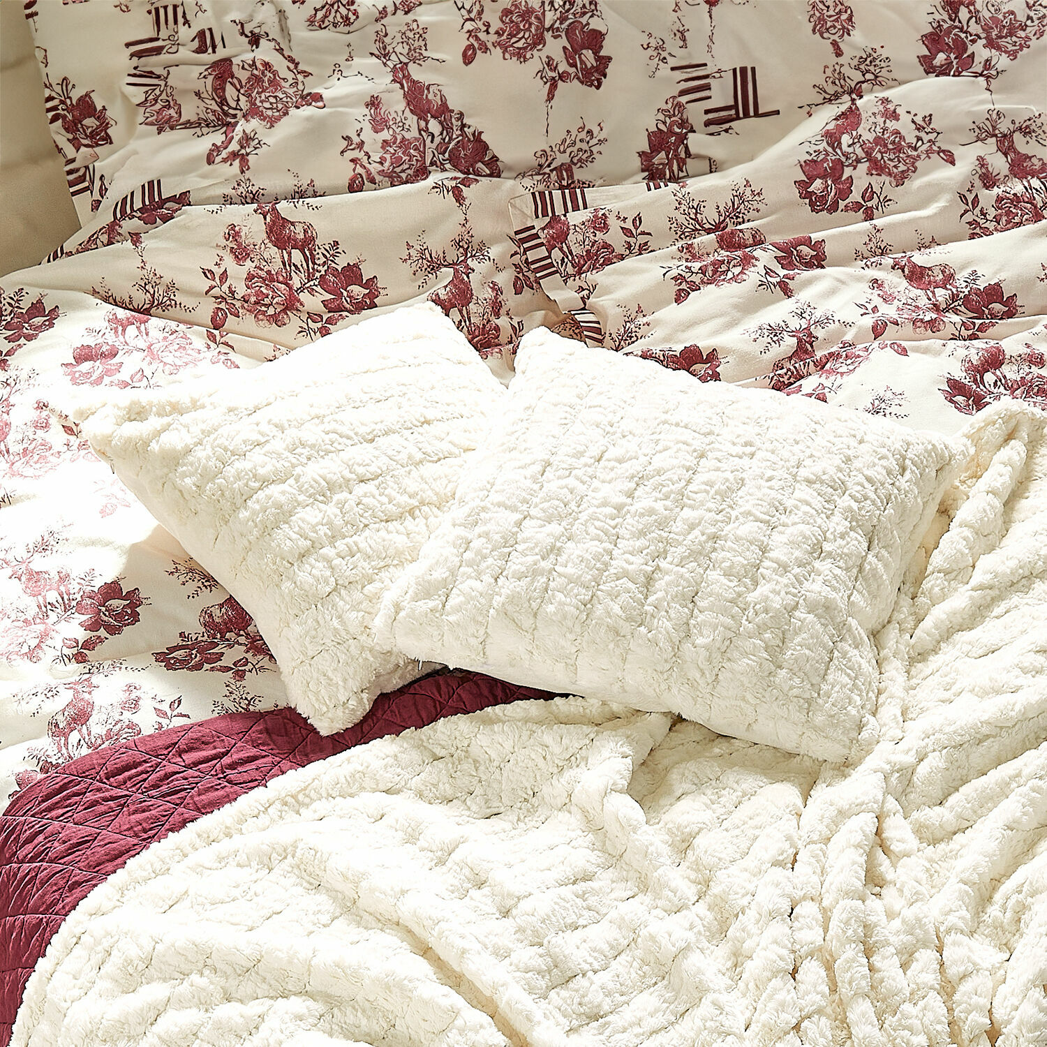 Kussenhoes Dorelice Crème zachte pluche kussens en dekens op bed met bordeaux bloemen- en hertenpatroon beddengoed