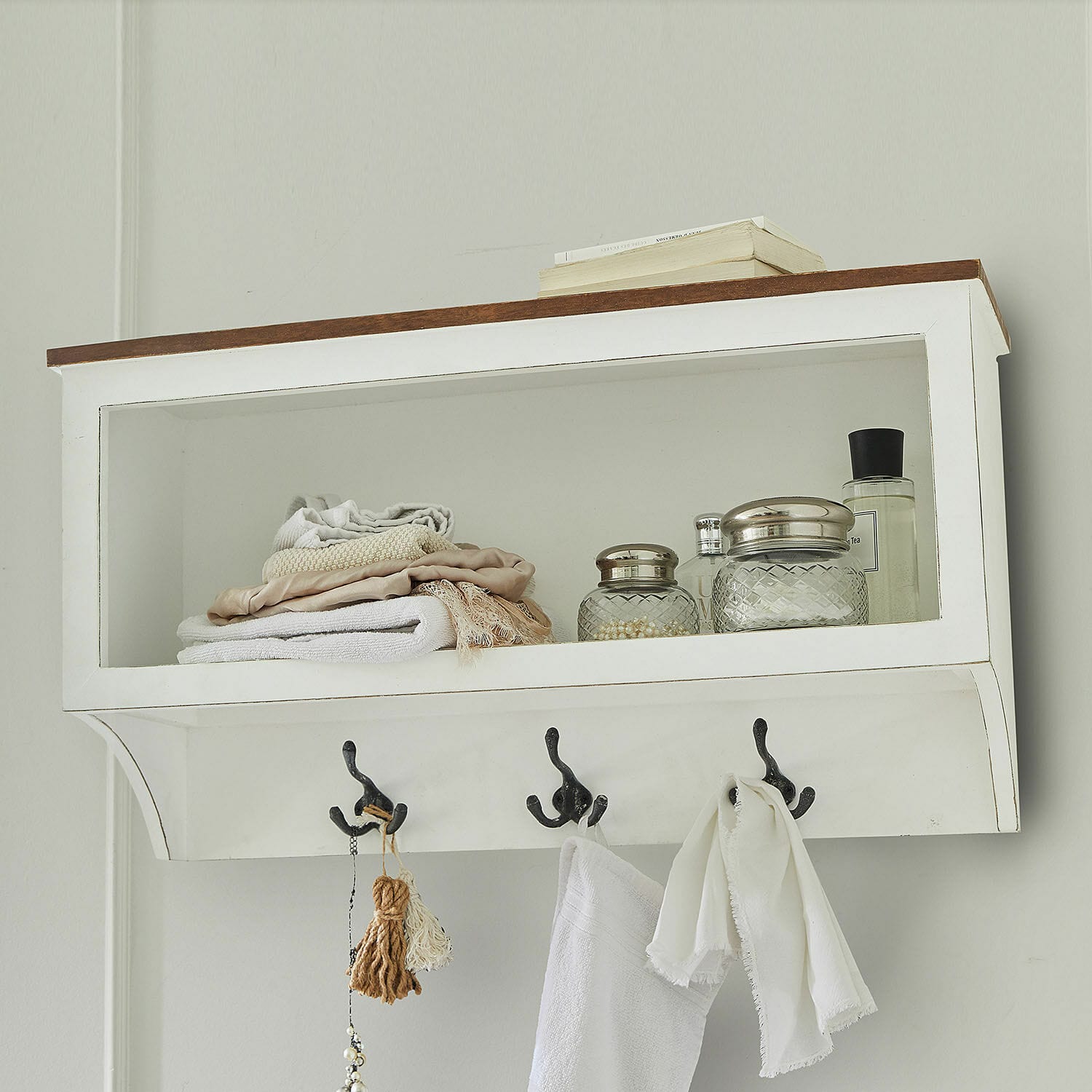 Witte houten wandplank met haken, handdoeken en glazen potten voor de badkamer