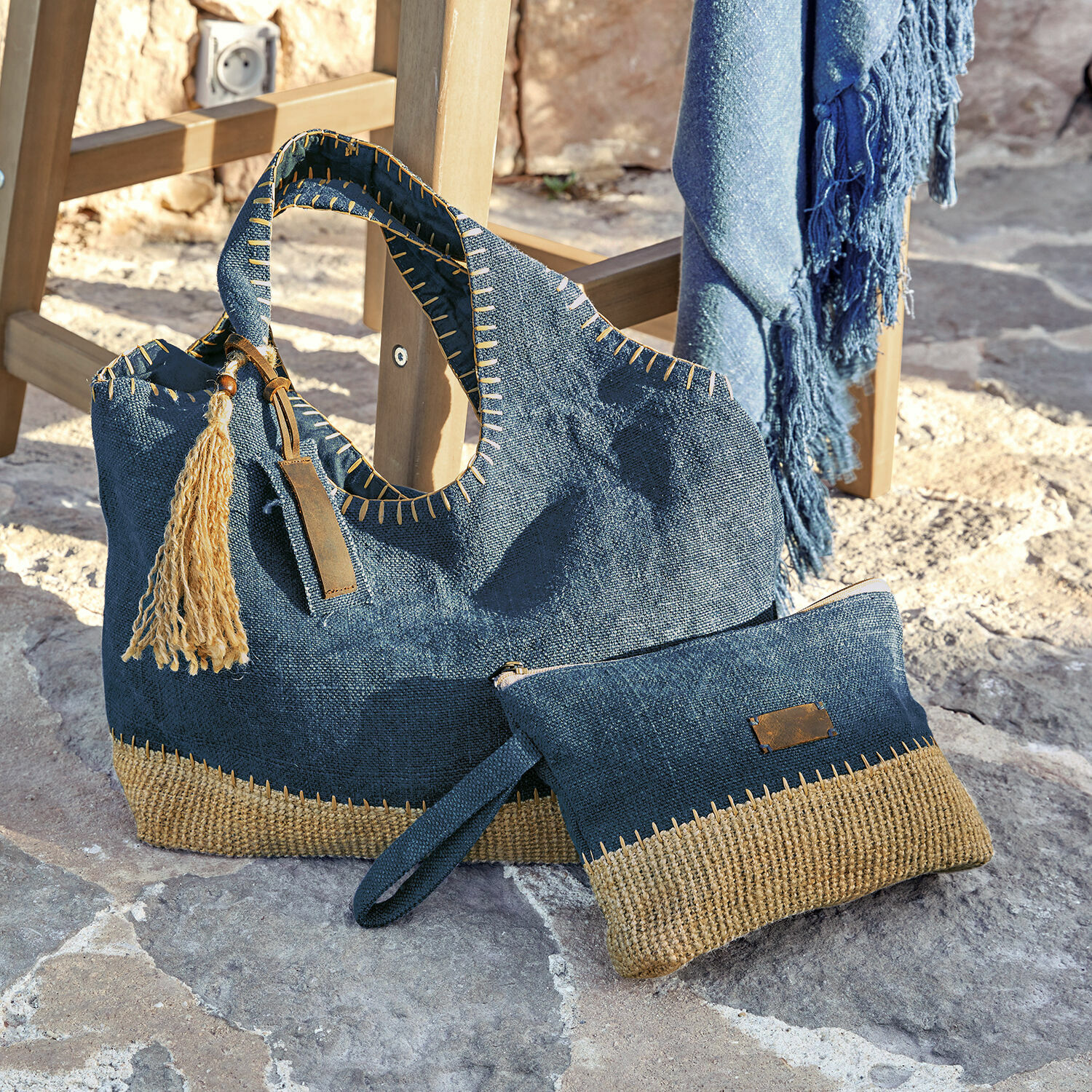 Donkerblauwe tas en make-uptasje van natuurlijk materiaal met beige details op stenen vloer
