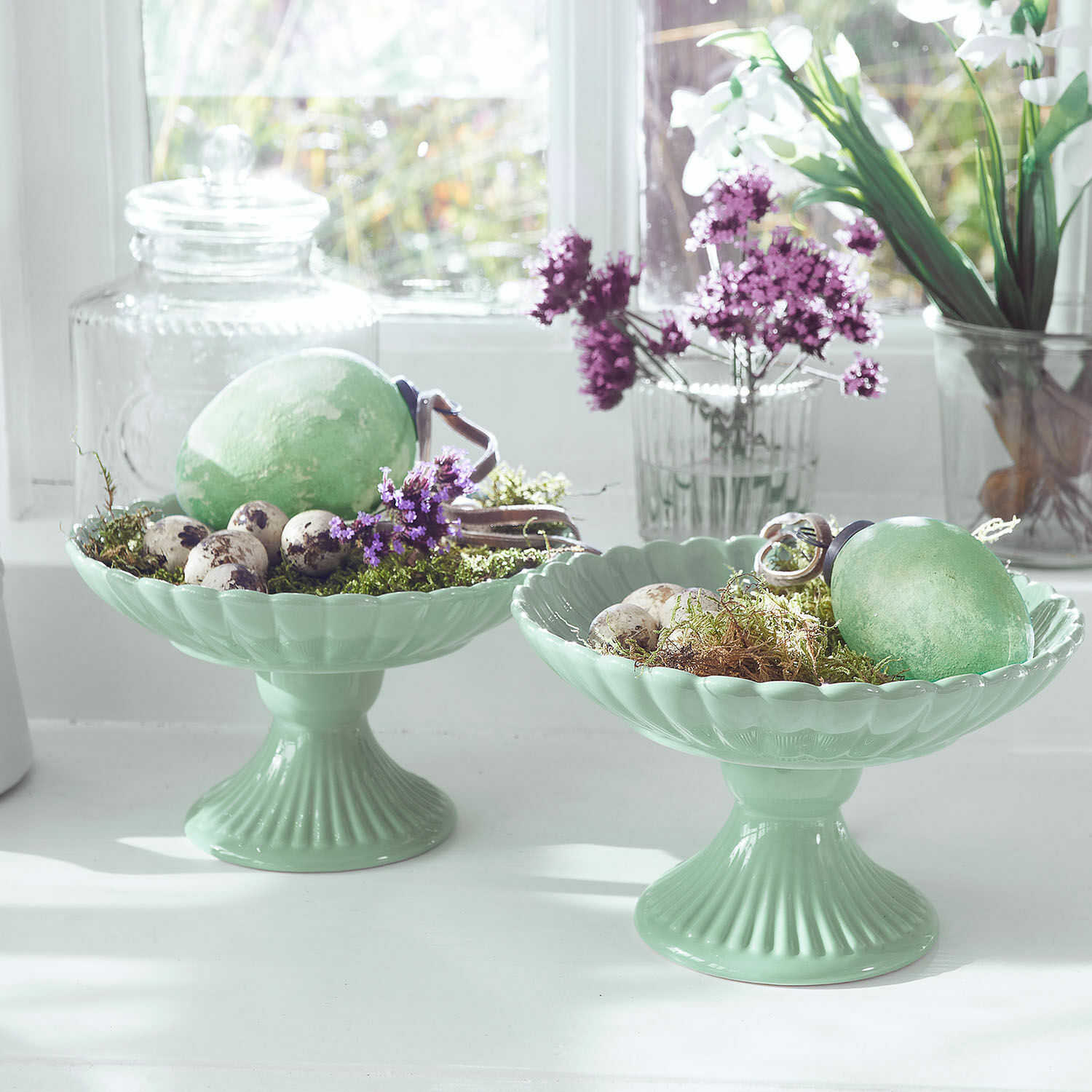 Groene keramische schalen op voet met eieren en bloemen, lichte lentebloemendecoratie