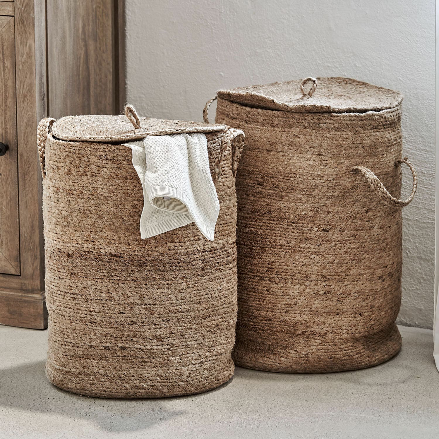 Twee ronde wasmanden van natuurlijke beige jute met deksels en handvatten