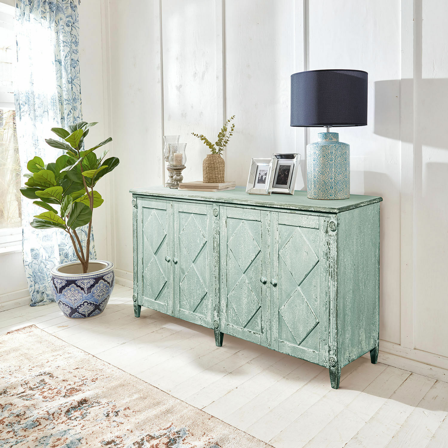 Mintgroene houten dressoir met vier deuren in vintage stijl met lamp en decoratie in lichte woonkamer