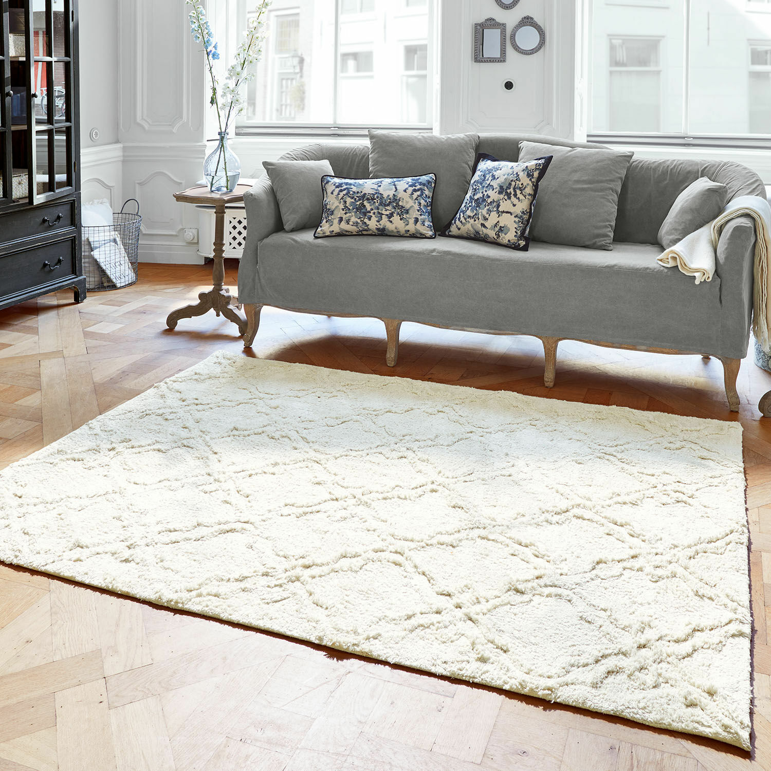 Lichte vloerkleed van zacht materiaal met geometrisch patroon in moderne woonkamer met grijze bank