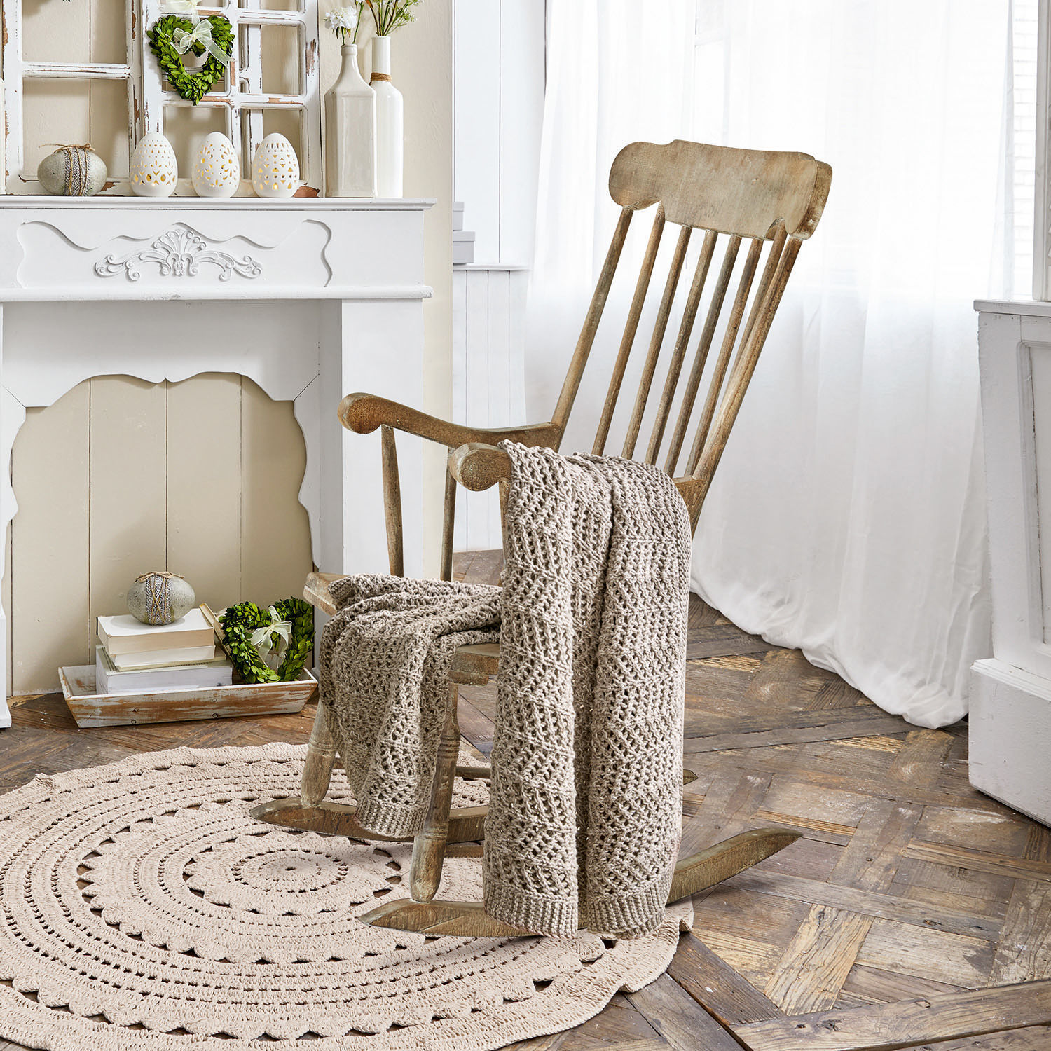 Schommelstoel Adaleine Houten schommelstoel met beige gehaakte deken op ronde vloerkleed in lichte kamer