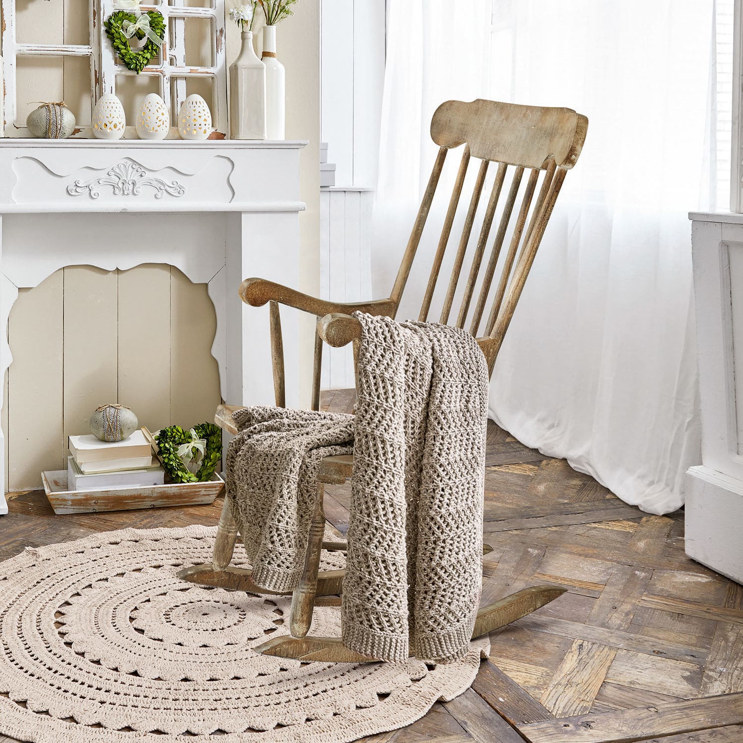 Schommelstoel Adaleine Houten schommelstoel met beige gehaakte deken op ronde vloerkleed in lichte kamer