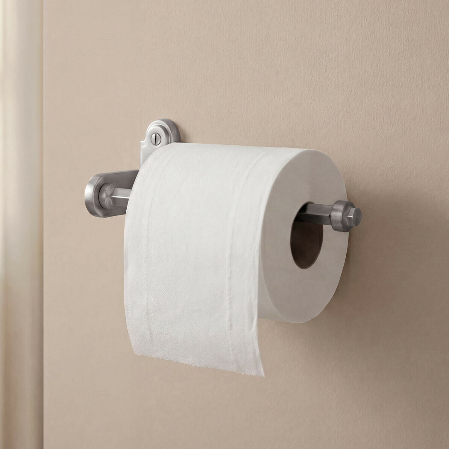 Metalen zilveren toiletrolhouder gemonteerd op een beige muur in de badkamer