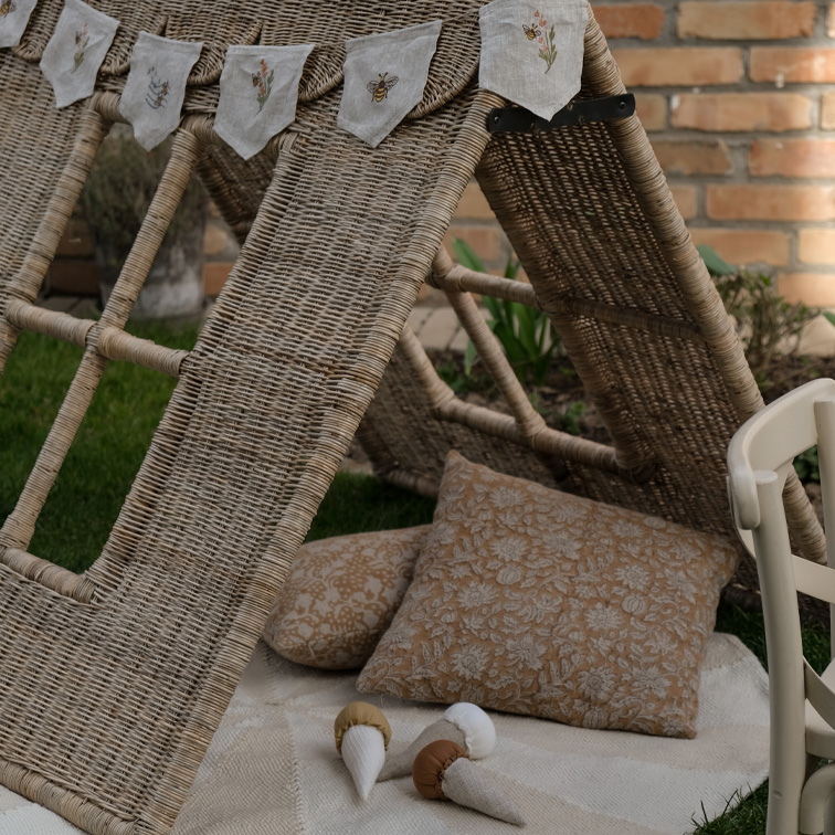 Rieten tent met kussens en geborduurde linnen slinger in de tuin, natuurlijke materialen en gezellige sfeer