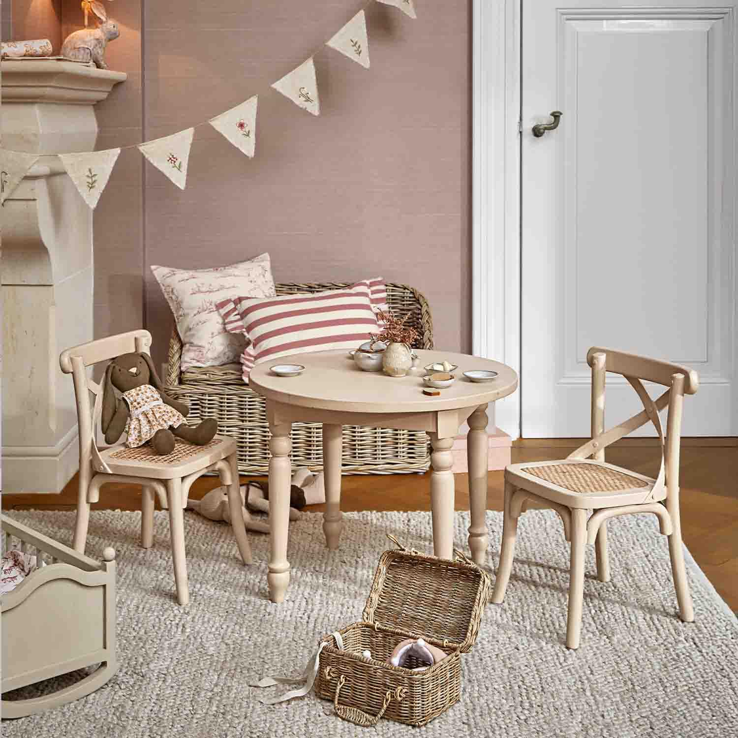 Ronde houten tafel en twee stoelen met gevlochten zitting in lichtbeige in kinderkamer