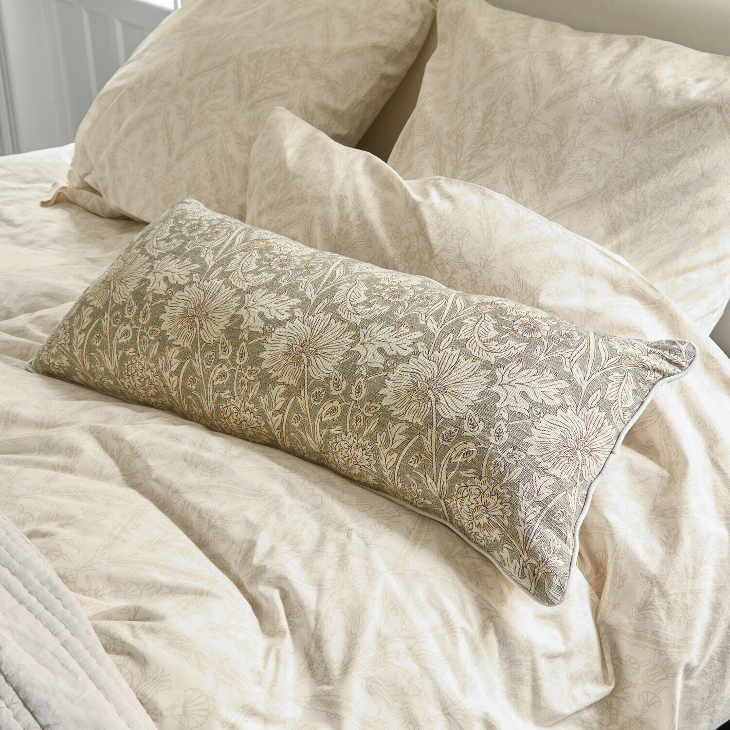 Beige beddengoed met subtiel bloemenpatroon en decoratief kussen met groene borduursels