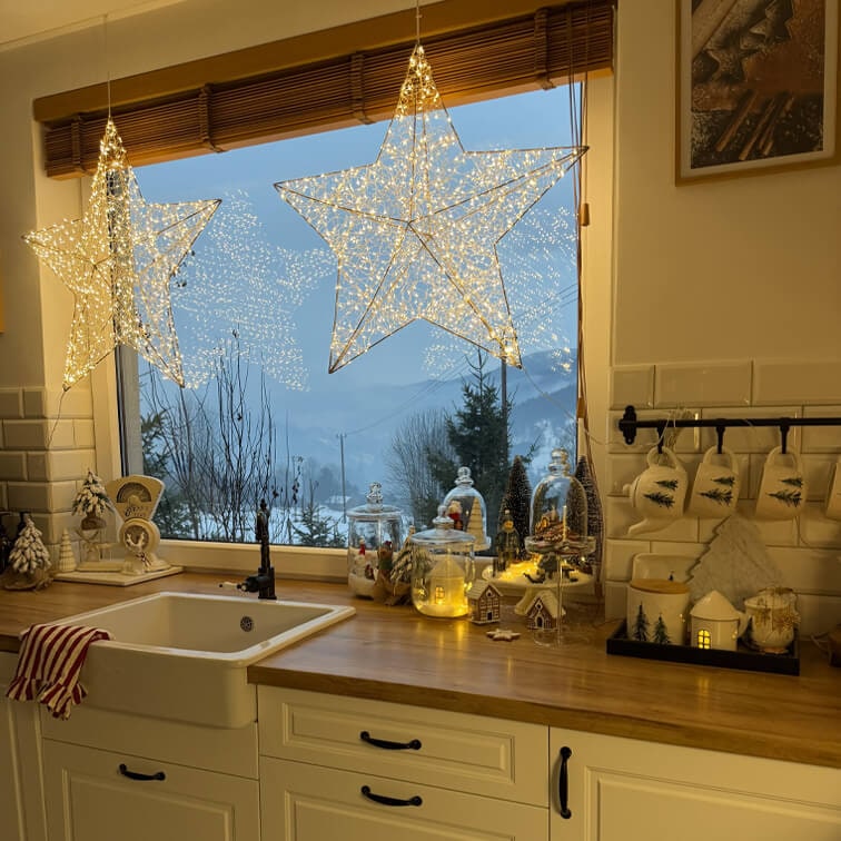 Verlichte sterdecoraties in keuken met houten werkblad en kerstversiering voor winterse buitenzicht