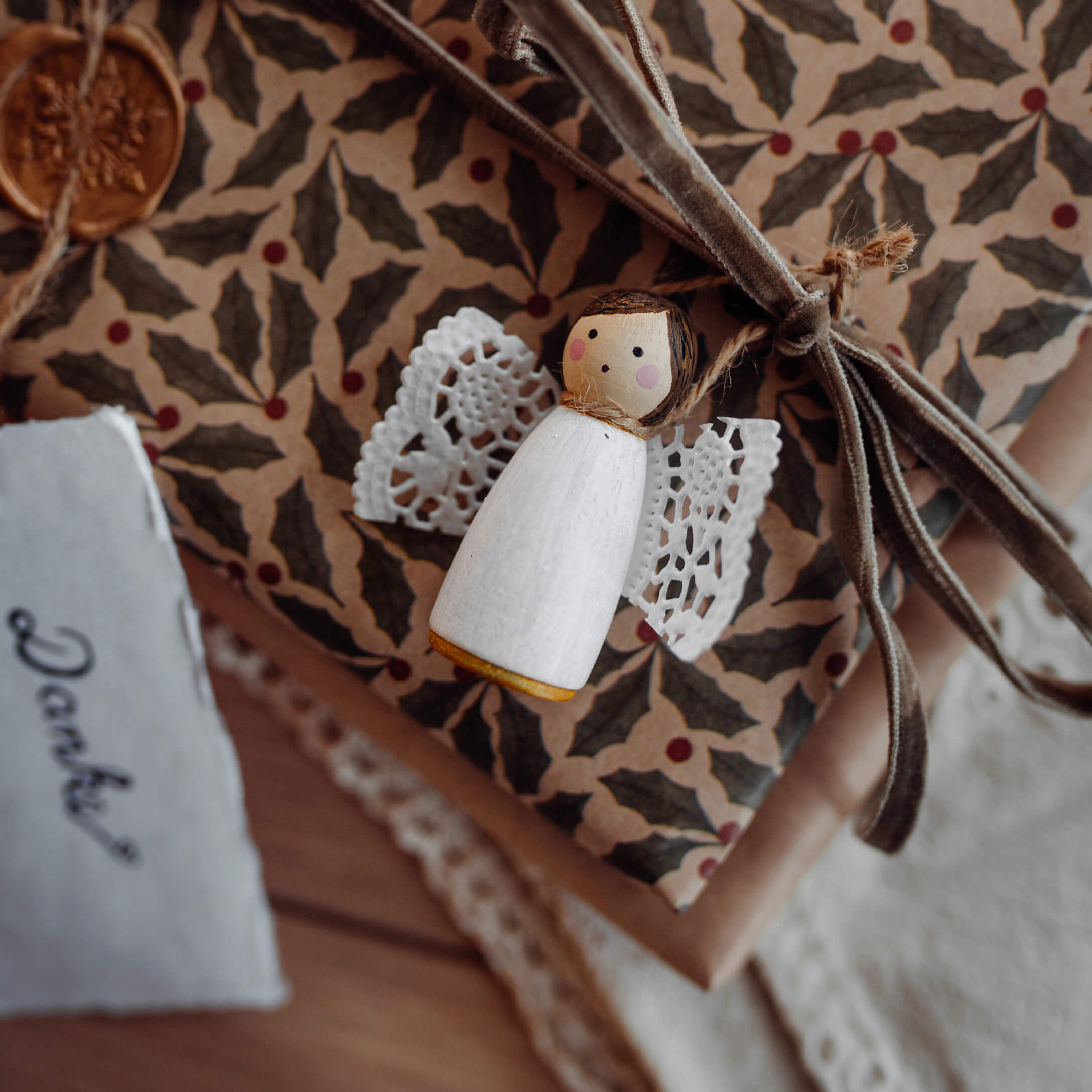 Witte houten engel met kanten vleugels op cadeau met decoratief papier en fluwelen strik