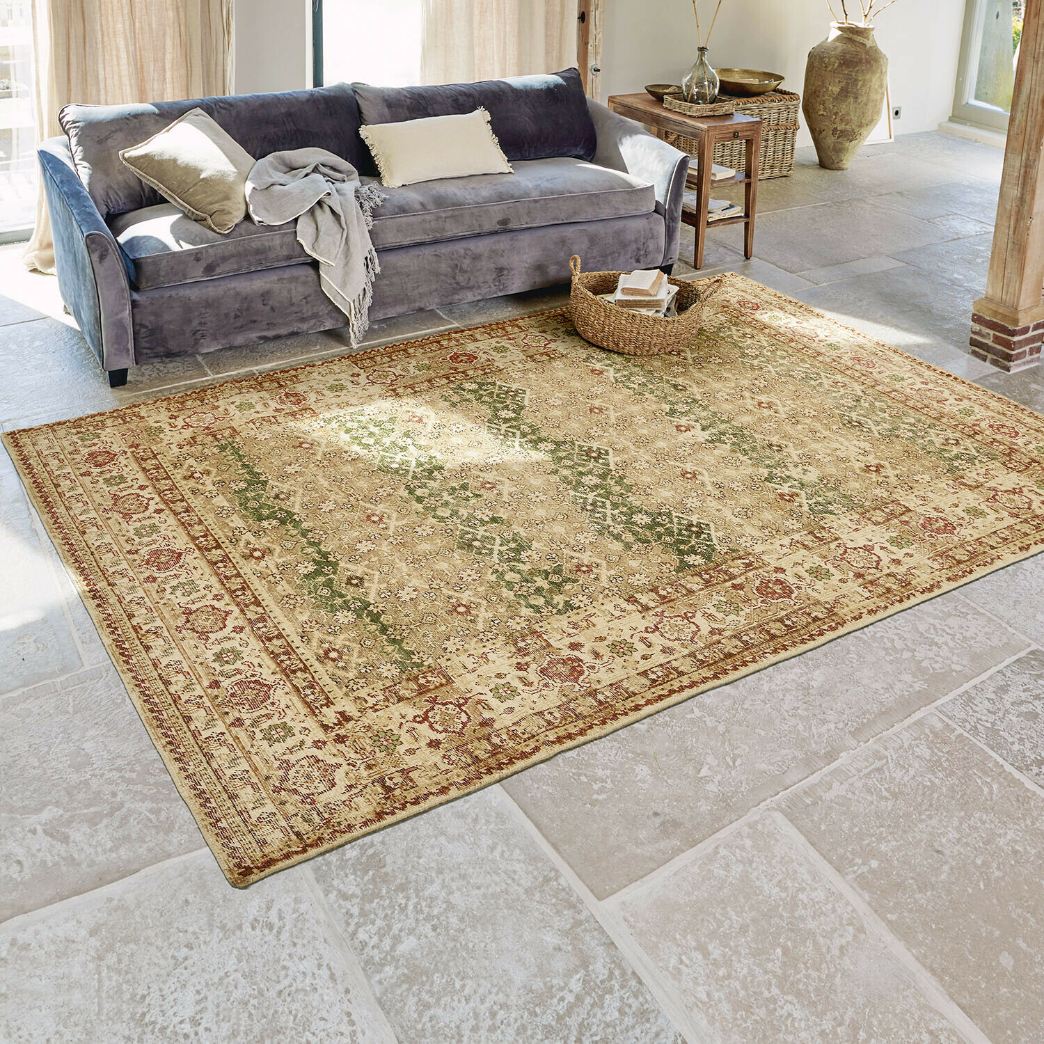 Vintage vloerkleed in warme beige en rode tinten op stenen vloer in woonkamer met grijze bank