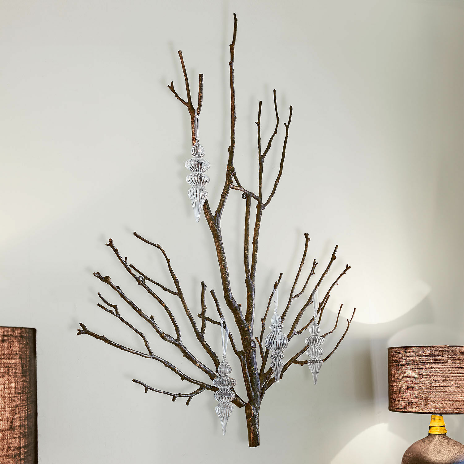 Decoratieve wandtak van bruin metaal met transparante kerstversieringen voor binnen