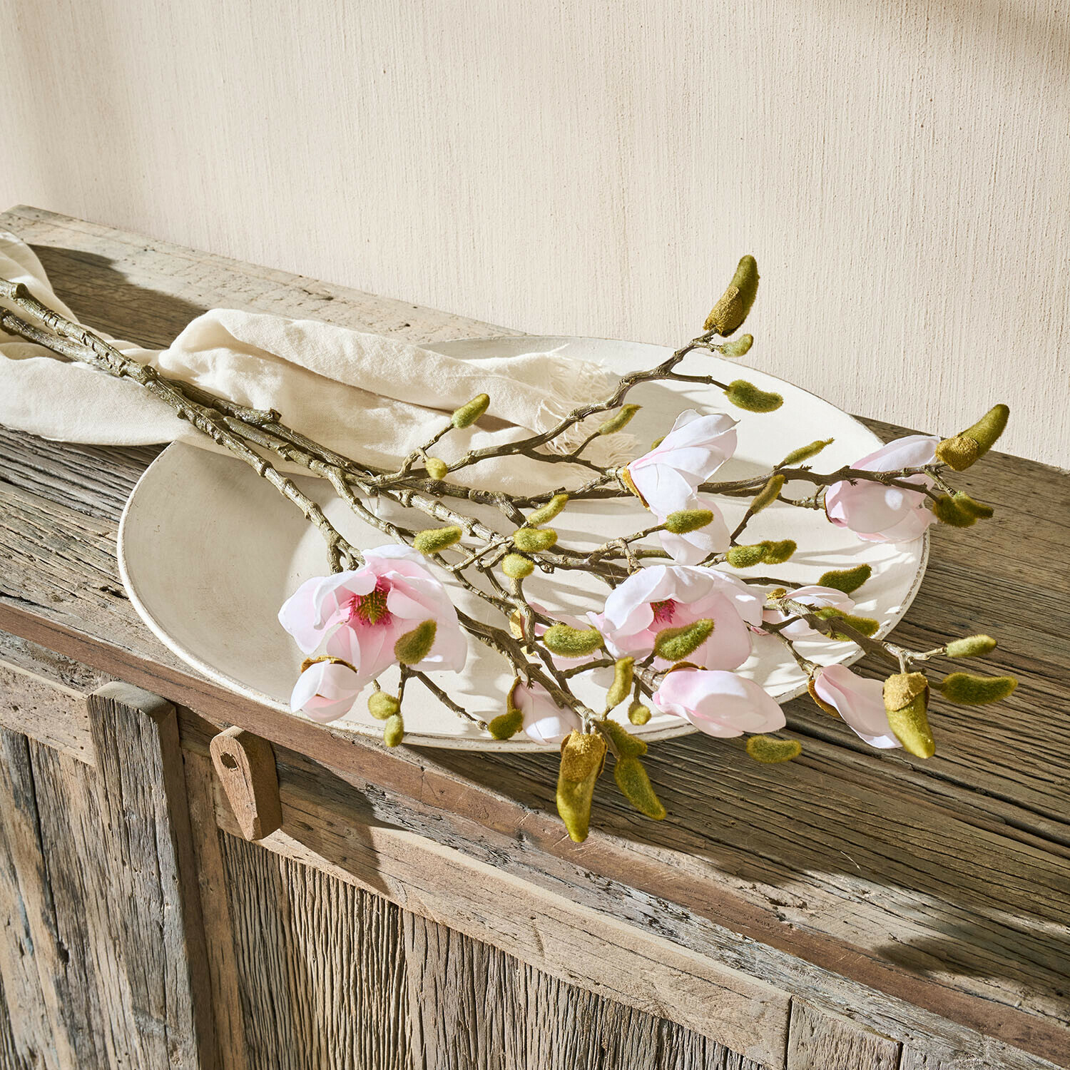 Decoratieve bloem set van 2 Aurélines Magnoliatakken met roze bloemen en groene knoppen op een wit bord op een rustieke houten tafel