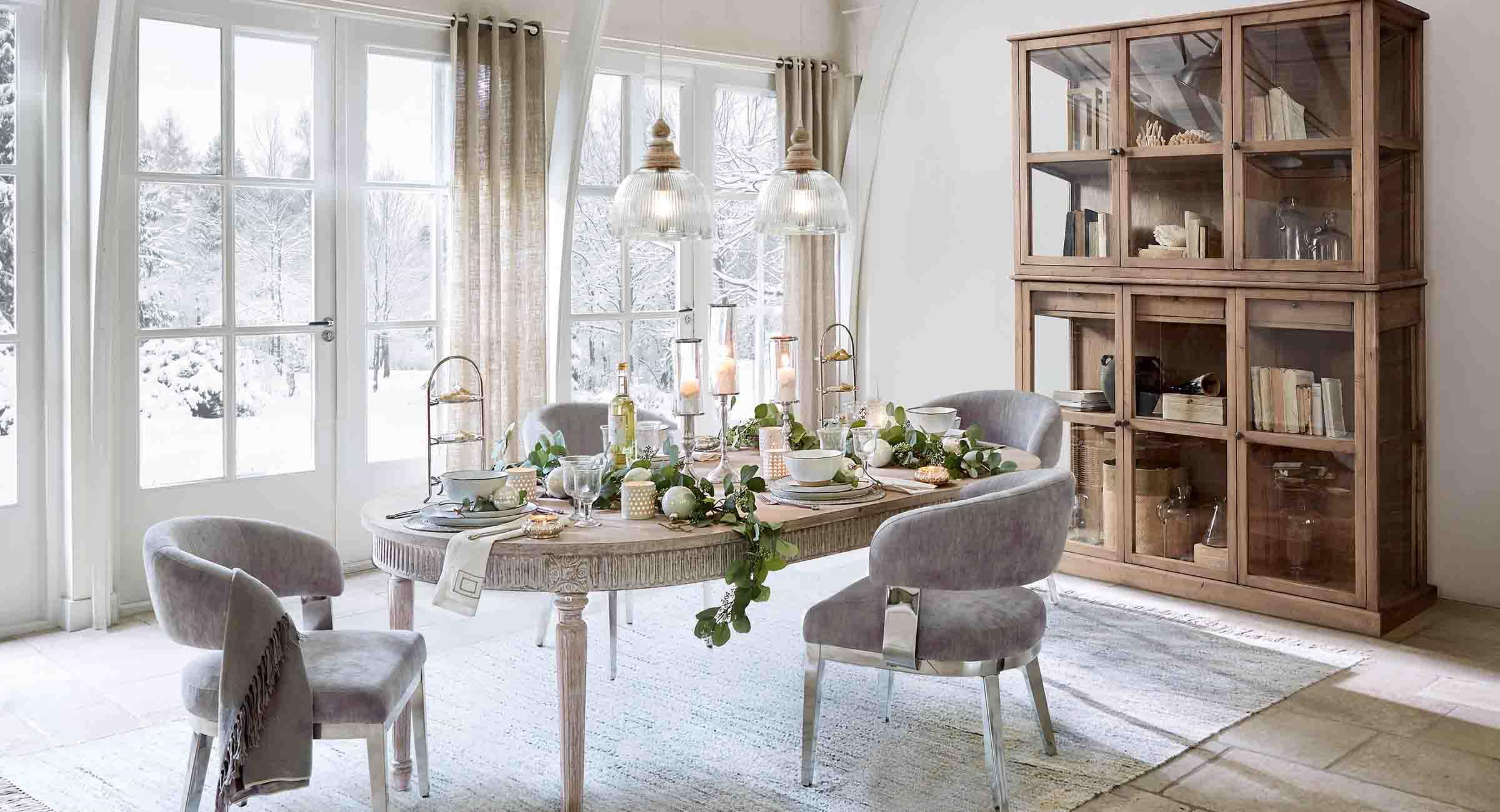 Eetkamer met houten tafel en grijze stoelen winterdecoratie met uitzicht op besneeuwde tuin