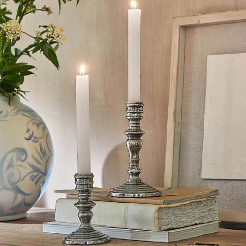Twee metalen kandelaars met witte kaarsen op oude boeken op een houten tafel