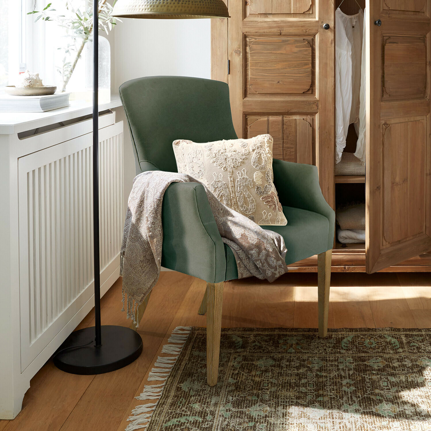 Stoel Hallmere Groene stoel met houten poten, crème kussen en grijze deken in gezellige ruimte met houten kast