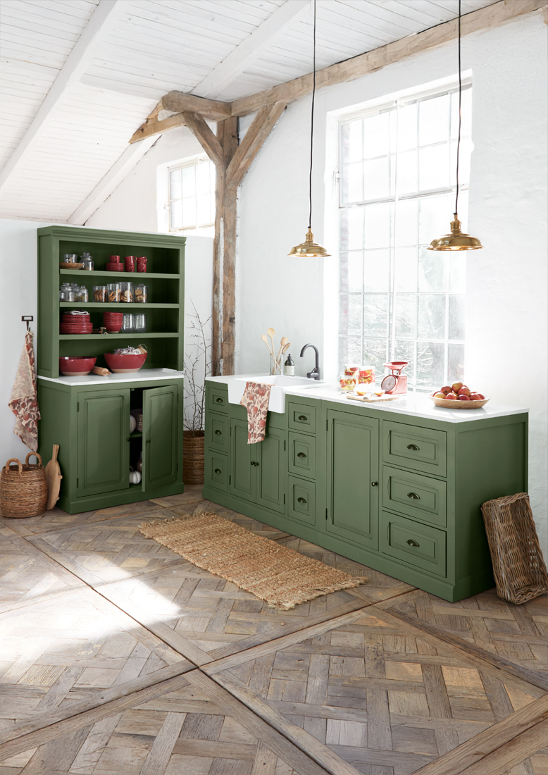 Groene houten keuken met wit werkblad en messing lampen in lichte, rustieke ruimte
