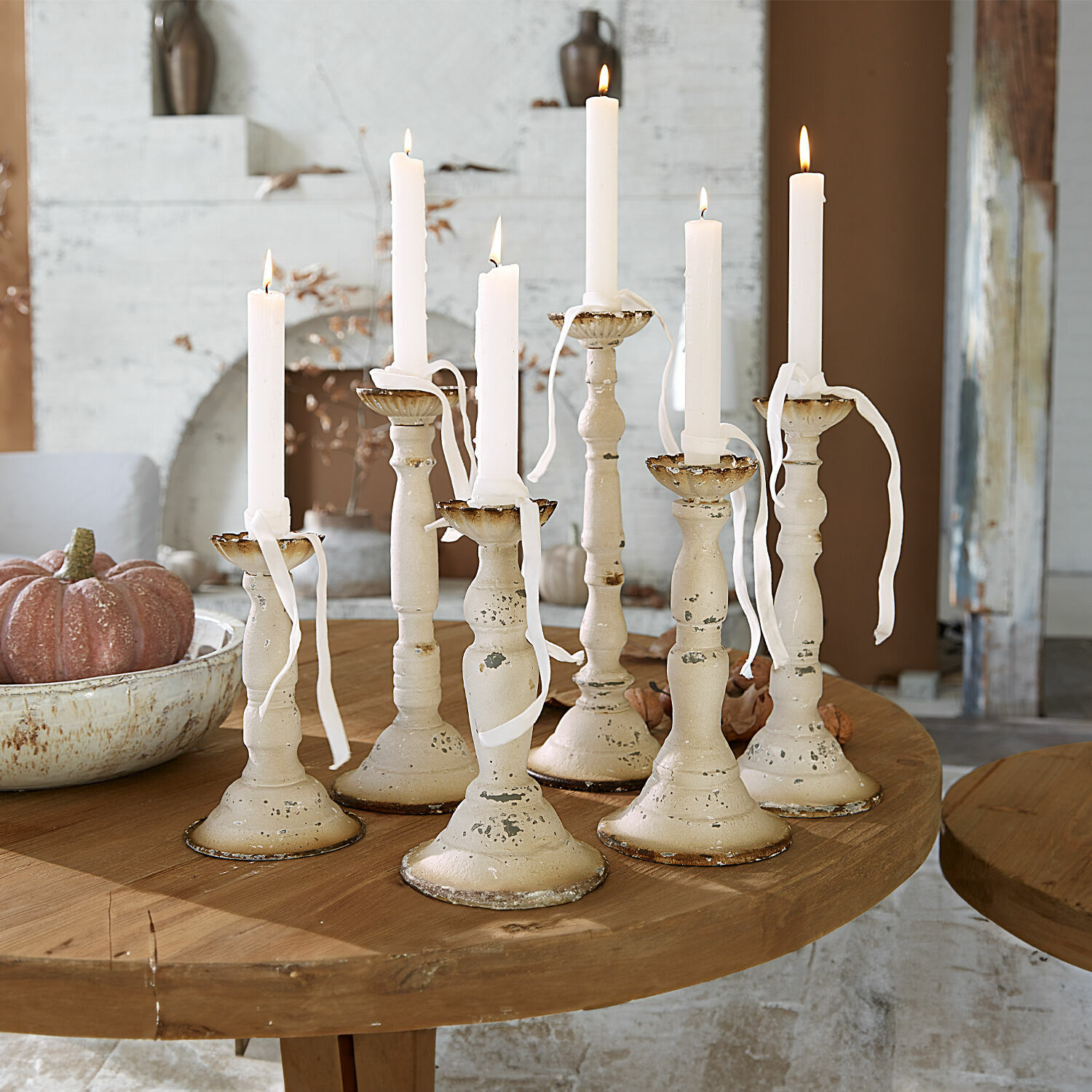 Set van zeven crèmekleurige metalen kandelaars met witte kaarsen op houten tafel, interieurdecoratie