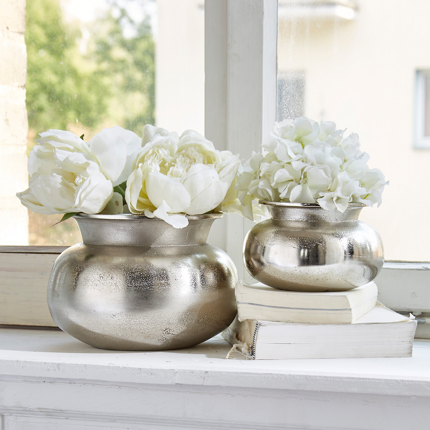 Vaas set van 2 Clément Twee zilverkleurige metalen vazen met witte bloemen op vensterbank, vintage interieurdecoratie