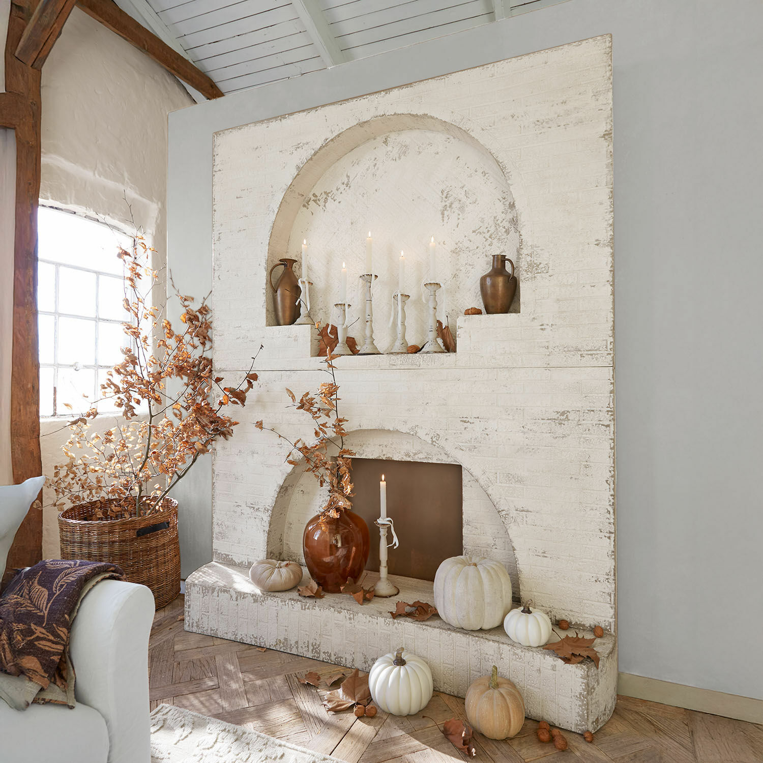 Haardschouw Forêt Émeraude Witte stenen open haard met herfstdecoratie en kaarsen in rustieke kamer