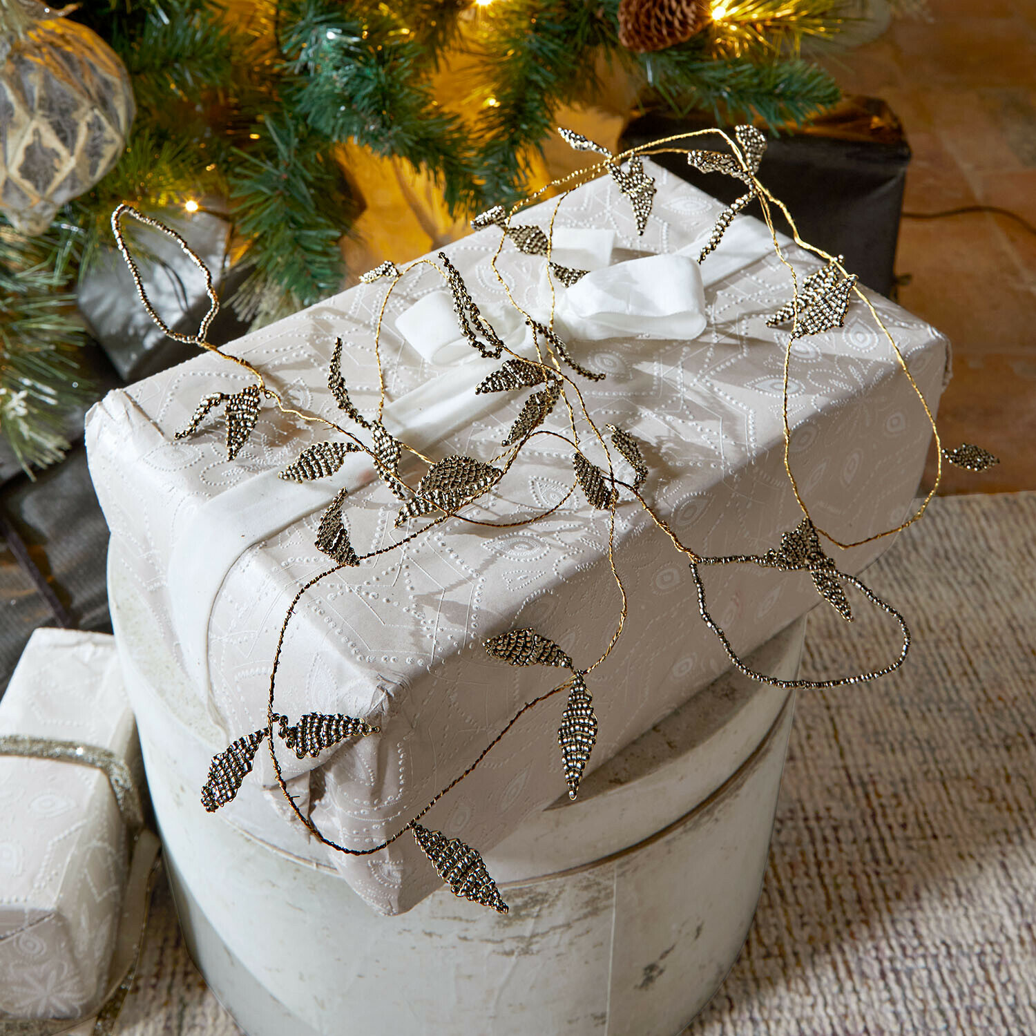 Stijlvol ingepakt cadeau in wit papier met fijn patroon en metalen bladversiering