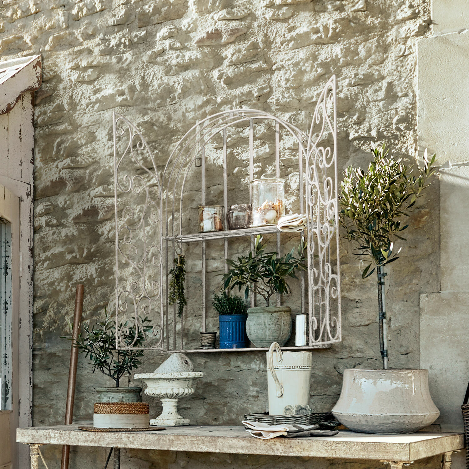 Wandrek Chambellay Witte metalen wandplank met decoratieve deuren en bloempotten tegen stenen muur
