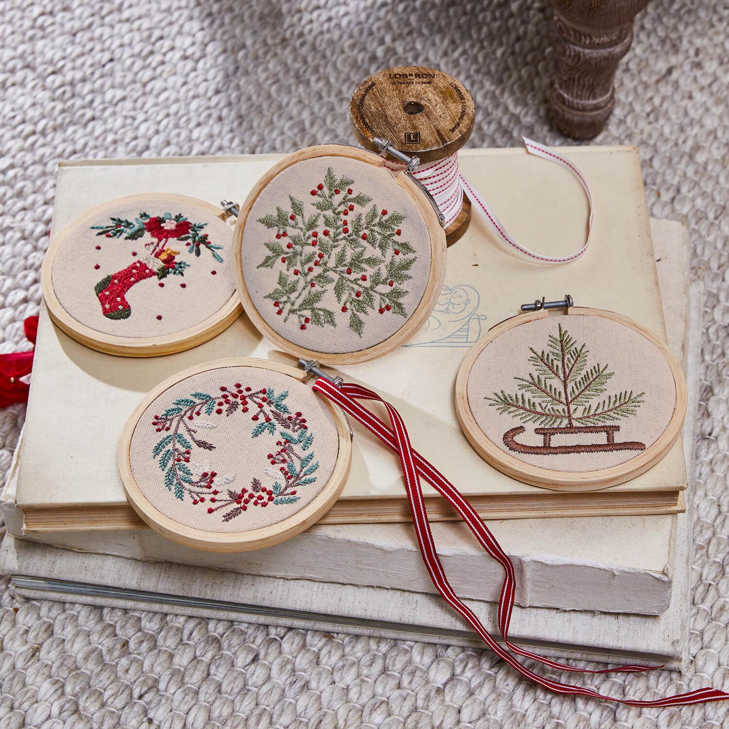 Set van vier geborduurde kerstversieringen met plantenmotieven en rode accenten op beige stof