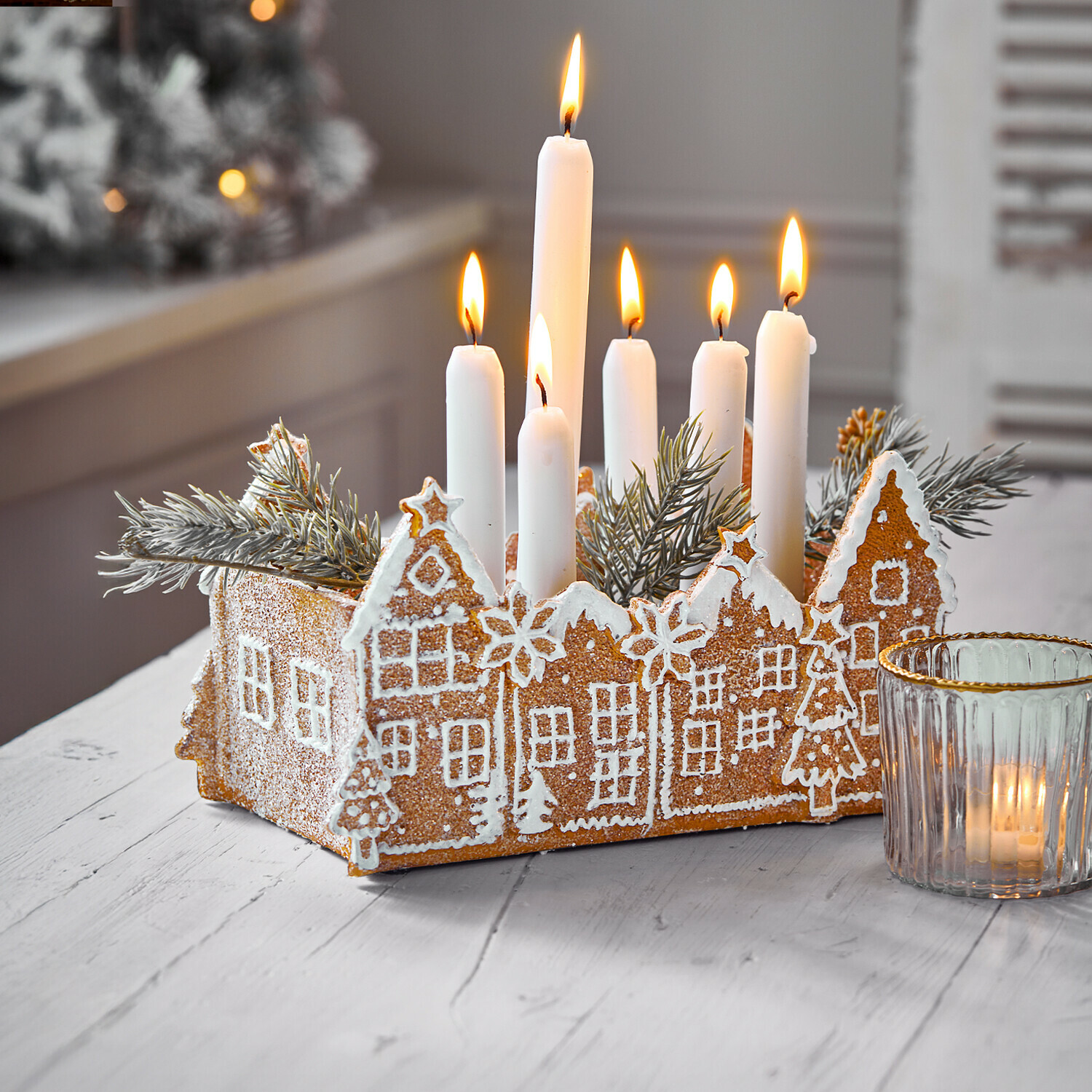 Adventskrans met peperkoekhuisjes en witte kaarsen als feestelijke kersttafelversiering