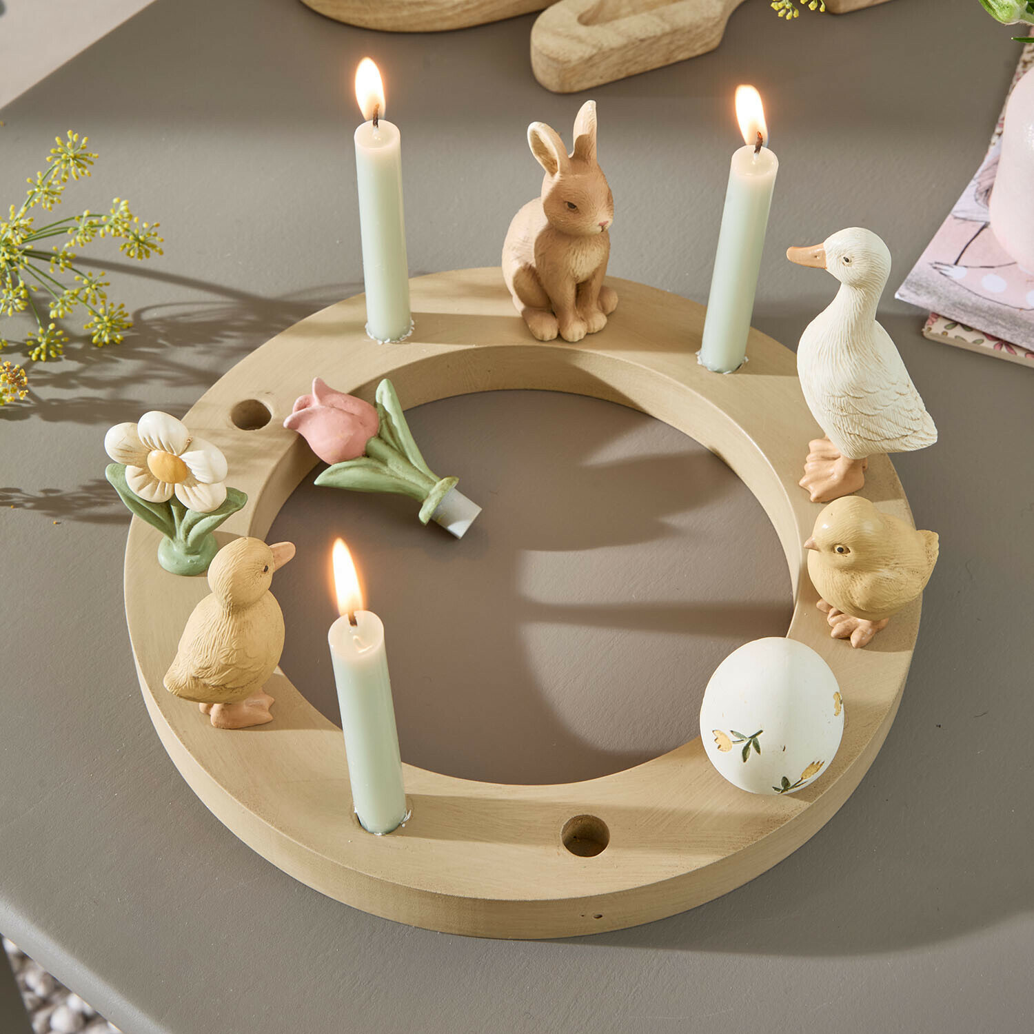 Ronde houten kandelaar met figuurtjes van konijn, eend en bloemen, drie brandende witte kaarsen