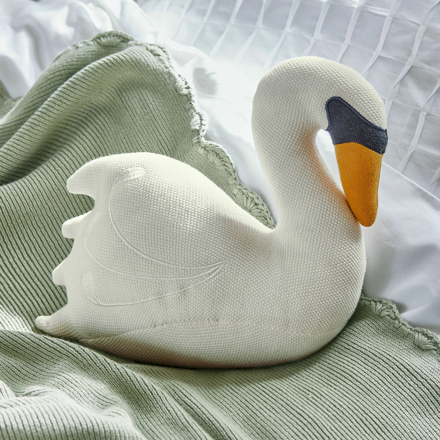 Knuffeltje Cariella Witte gebreide zwaanvormige kussen op groene deken, zachte slaapkamerdecoratie
