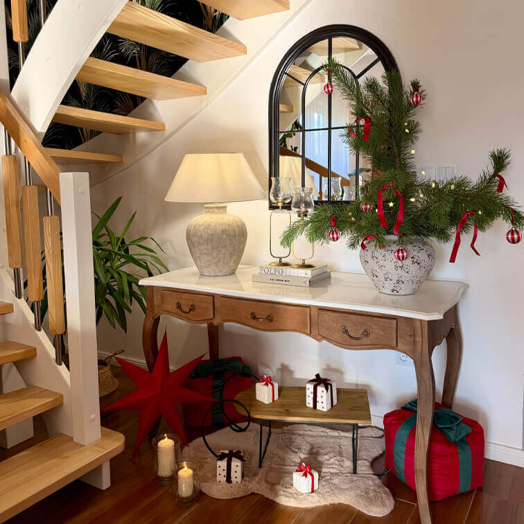 Houten tafel met marmeren blad, lamp en kerstdecoratie met groene takken en rode ornamenten