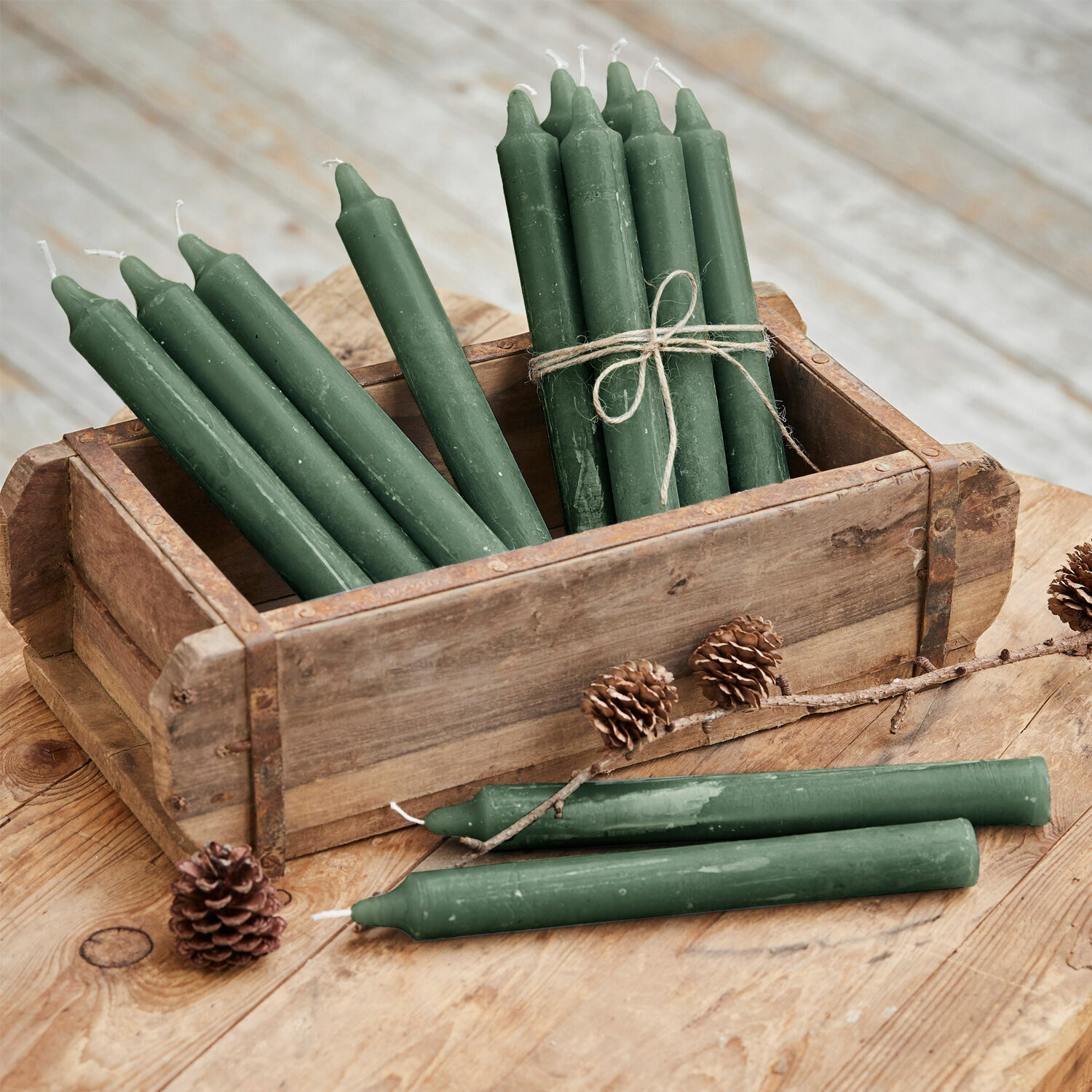 Set groene waskaarsen in houten doos op rustieke houten tafel geplaatst