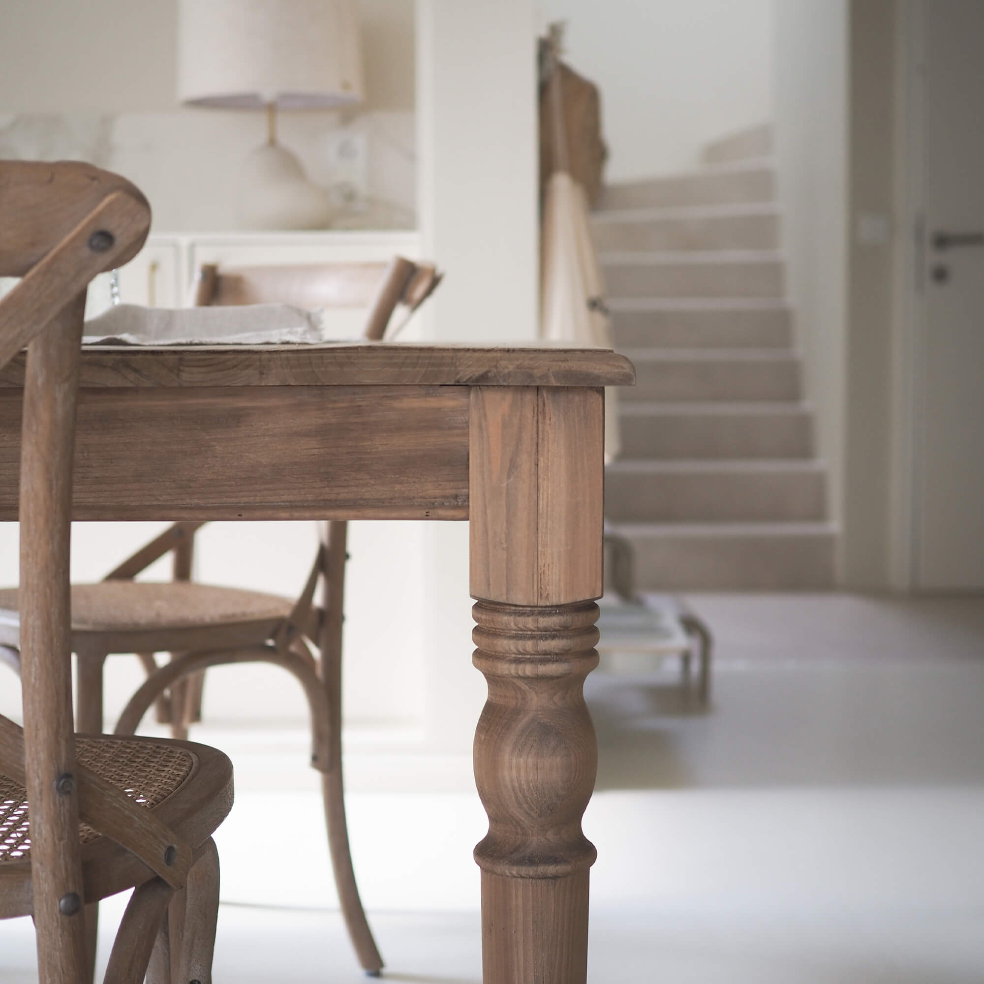 Houten tafel en stoelen in natuurlijke kleur in lichte, moderne ruimte met witte vloer